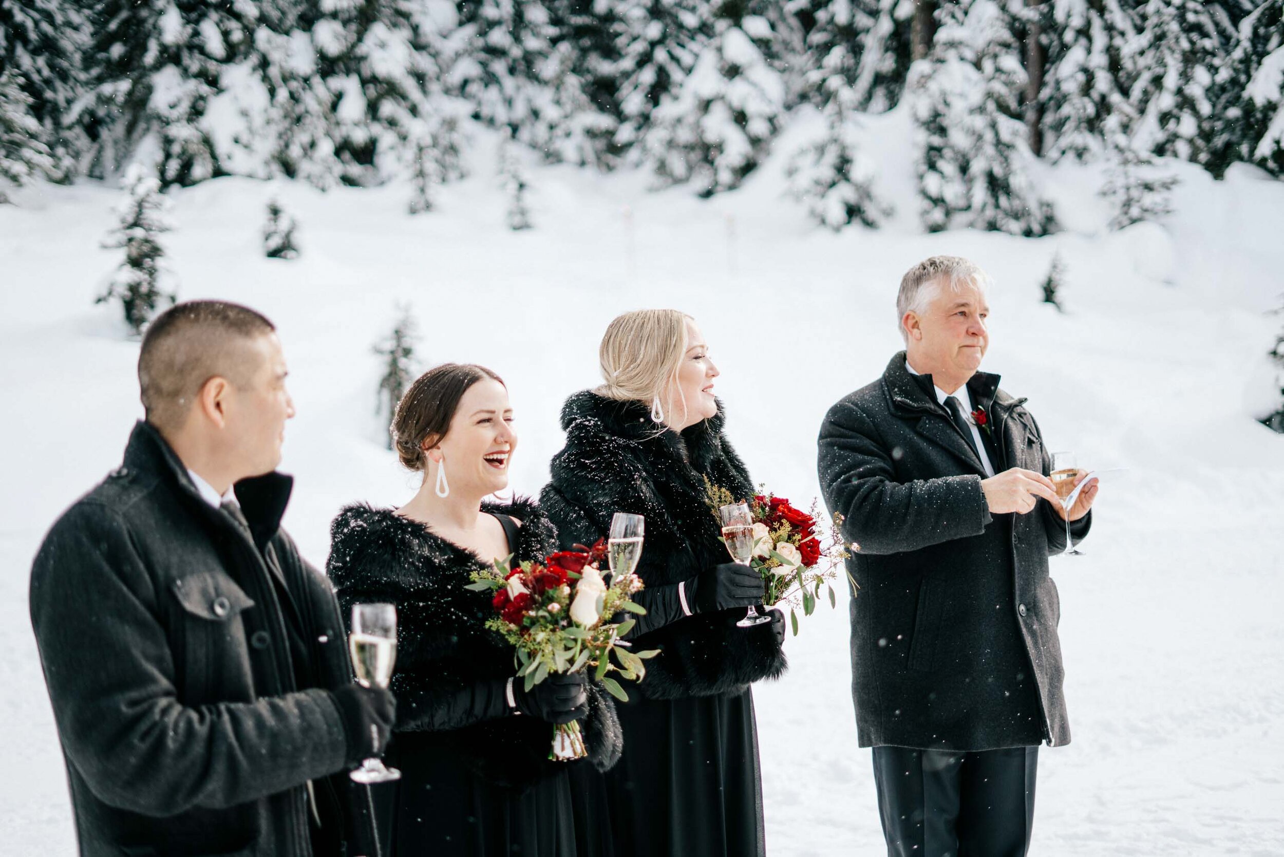 Outdoor Wedding guests smile as they toast the bride and groom in the snow.