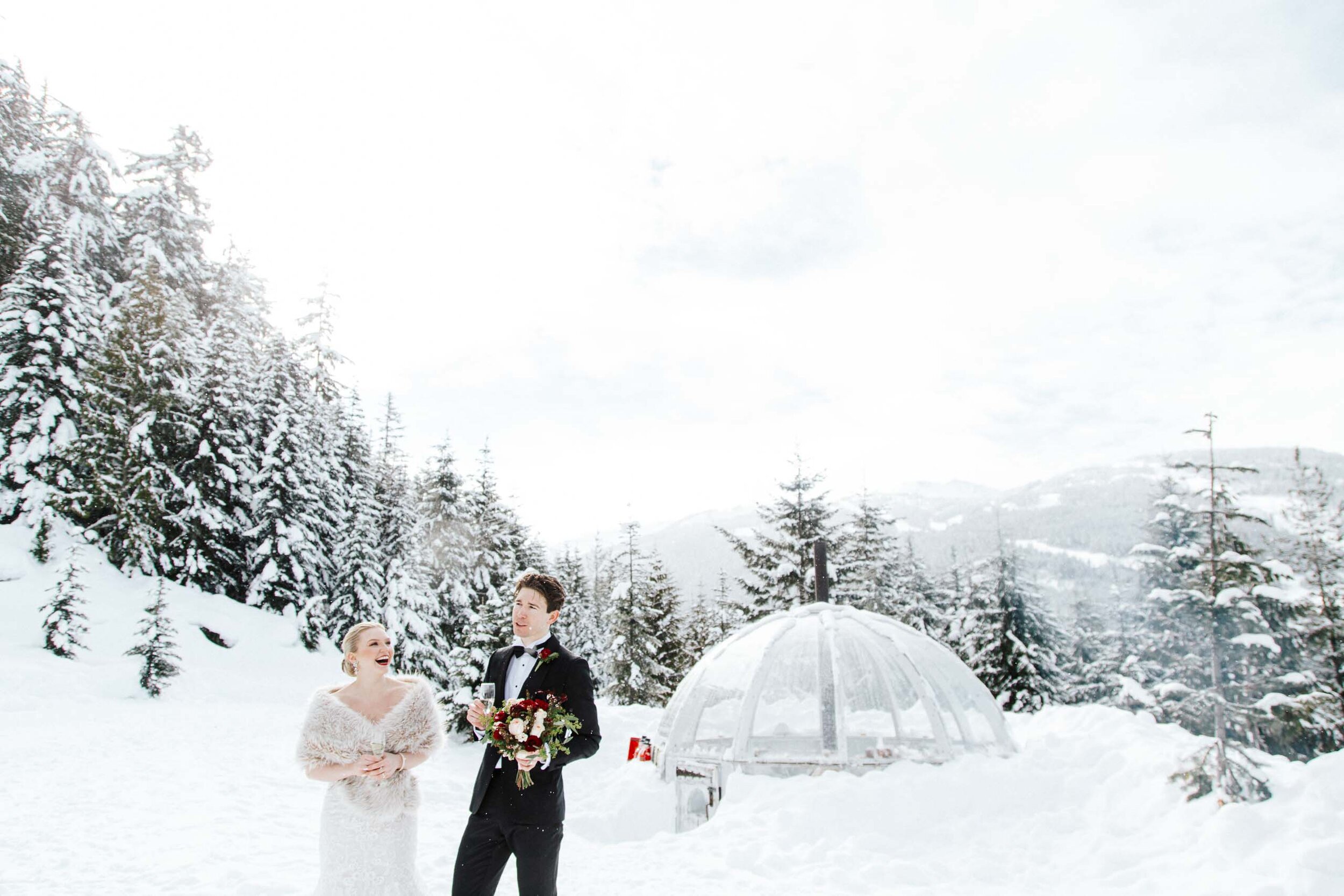 A bride and groom smile during a toast during their snowy outdoor Whistler Ceremony.