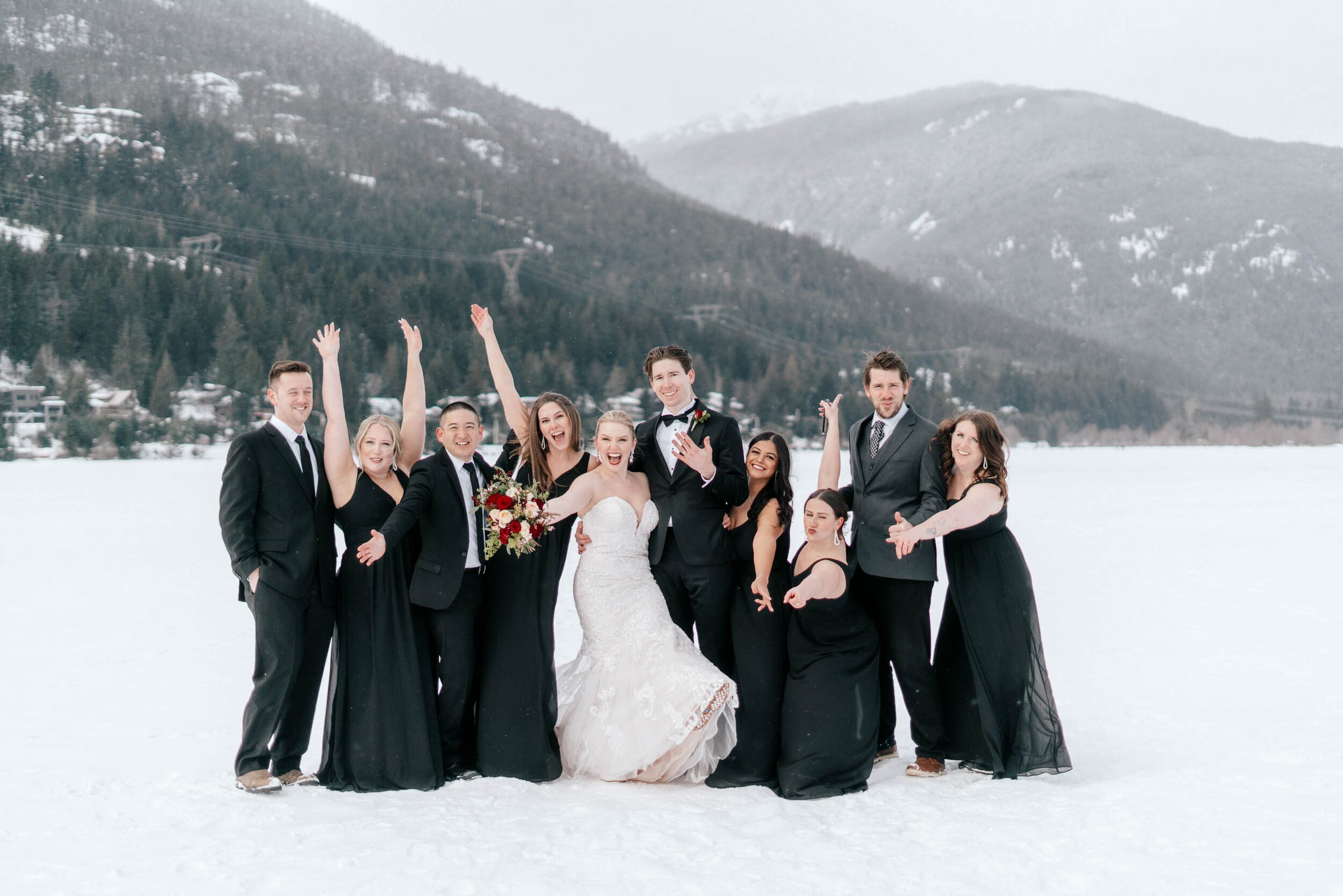 A wedding part cheers as they pose in the snow in Whistler, BC.