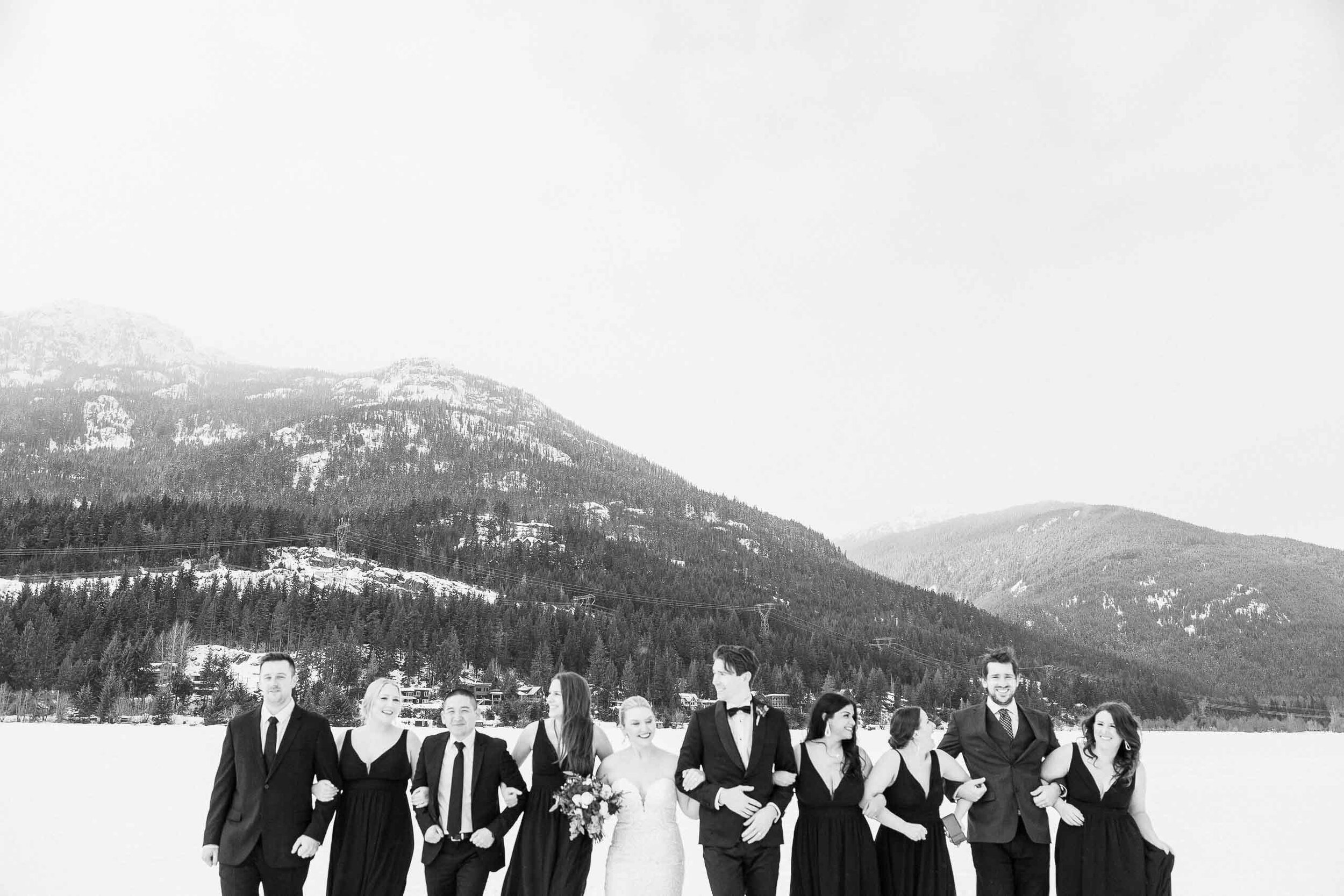 A wedding party strolls arm-in-arm through the snow in Whistler, BC.