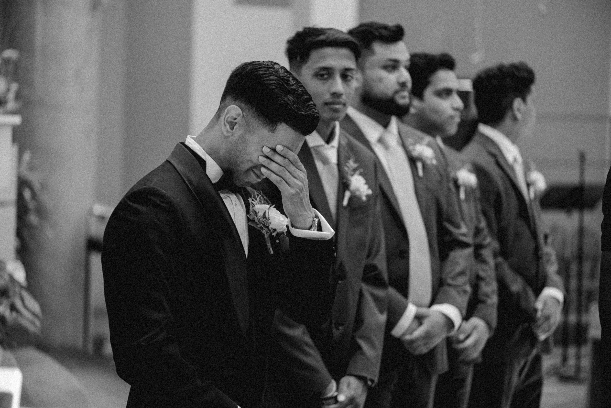 Groom wiping away tears during the wedding ceremony.