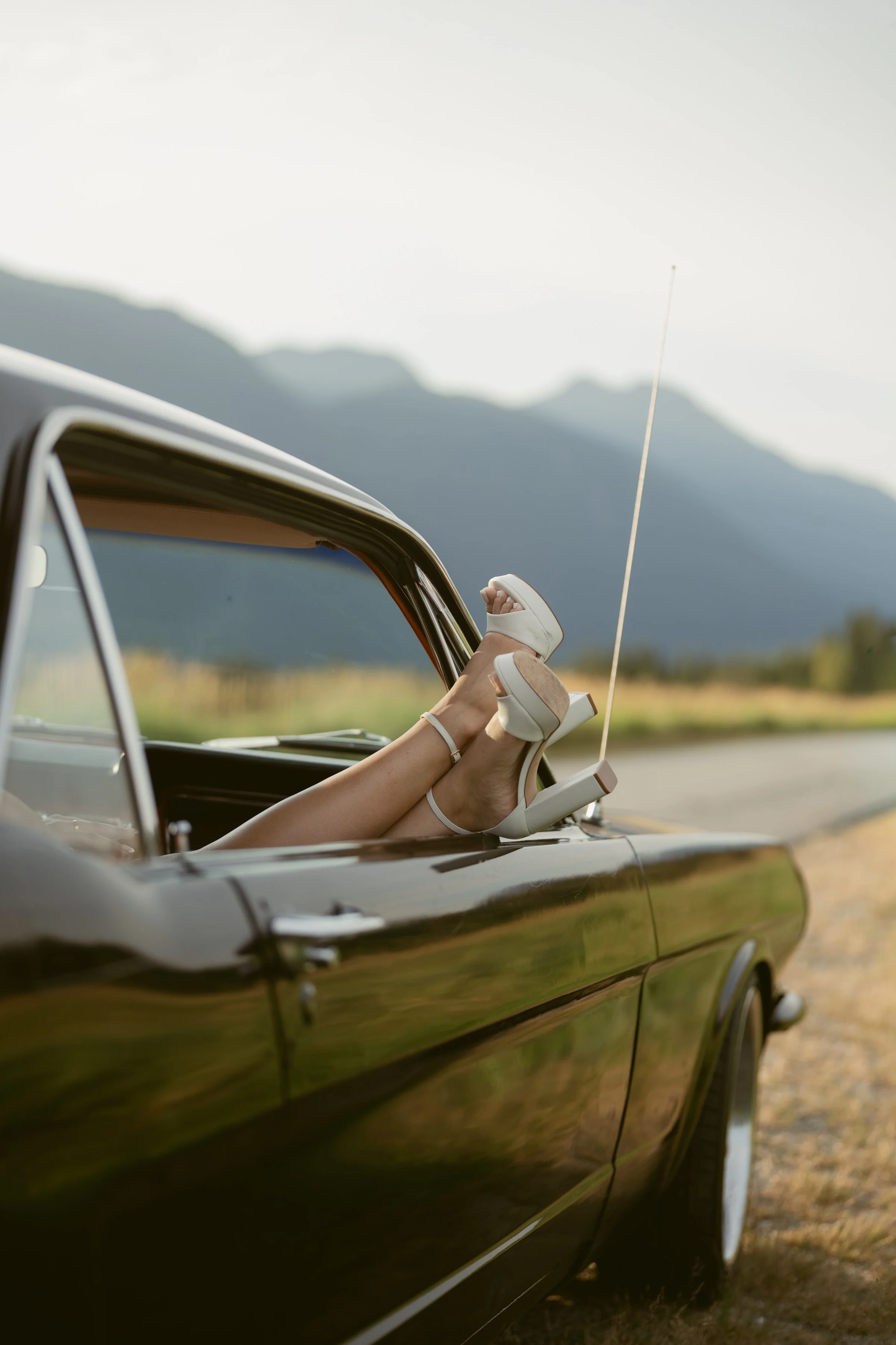Playful engagement photo in Pitt Lake with heels resting out a car window.