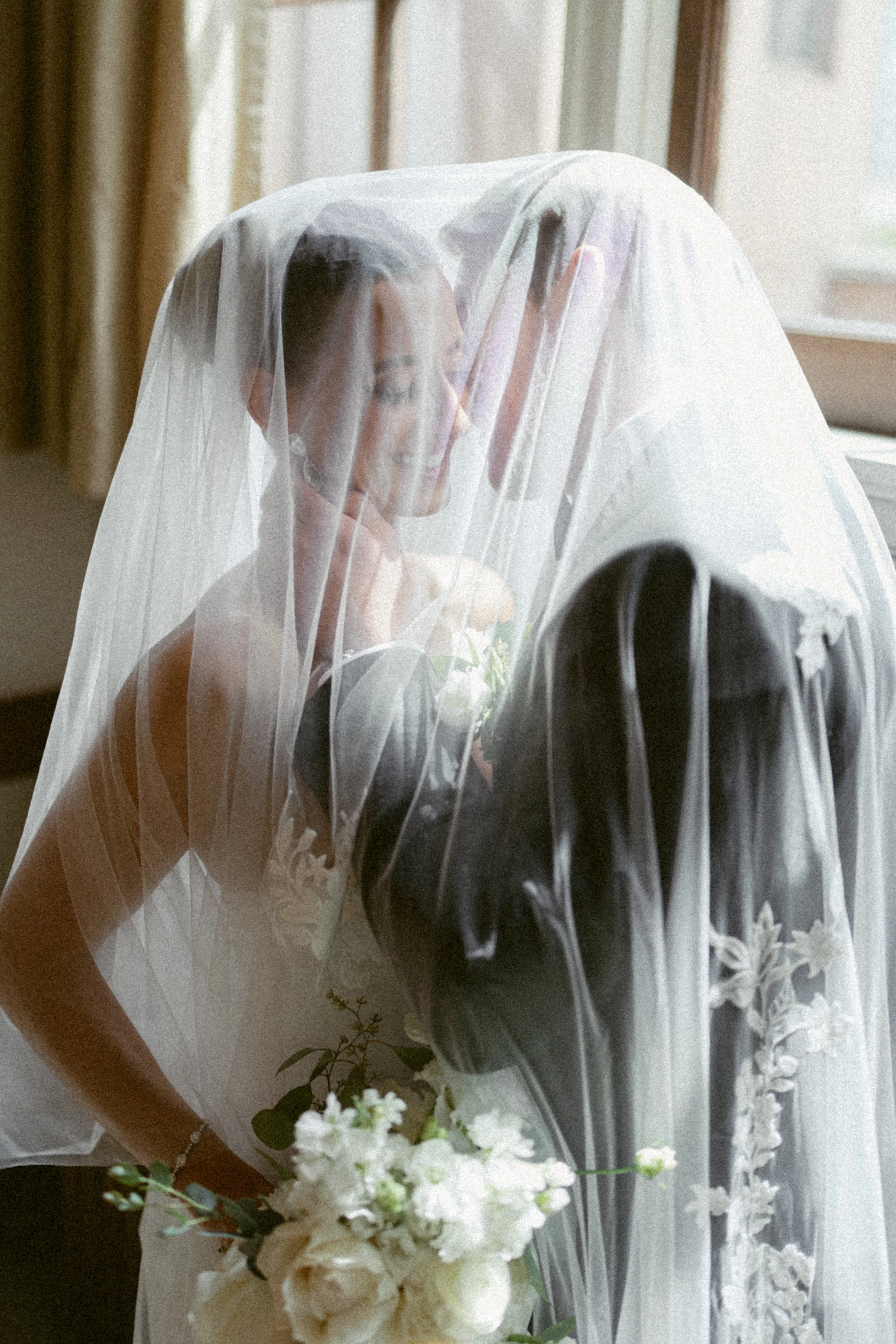 Bride and groom under veil at Vancouver Club with window lighting.