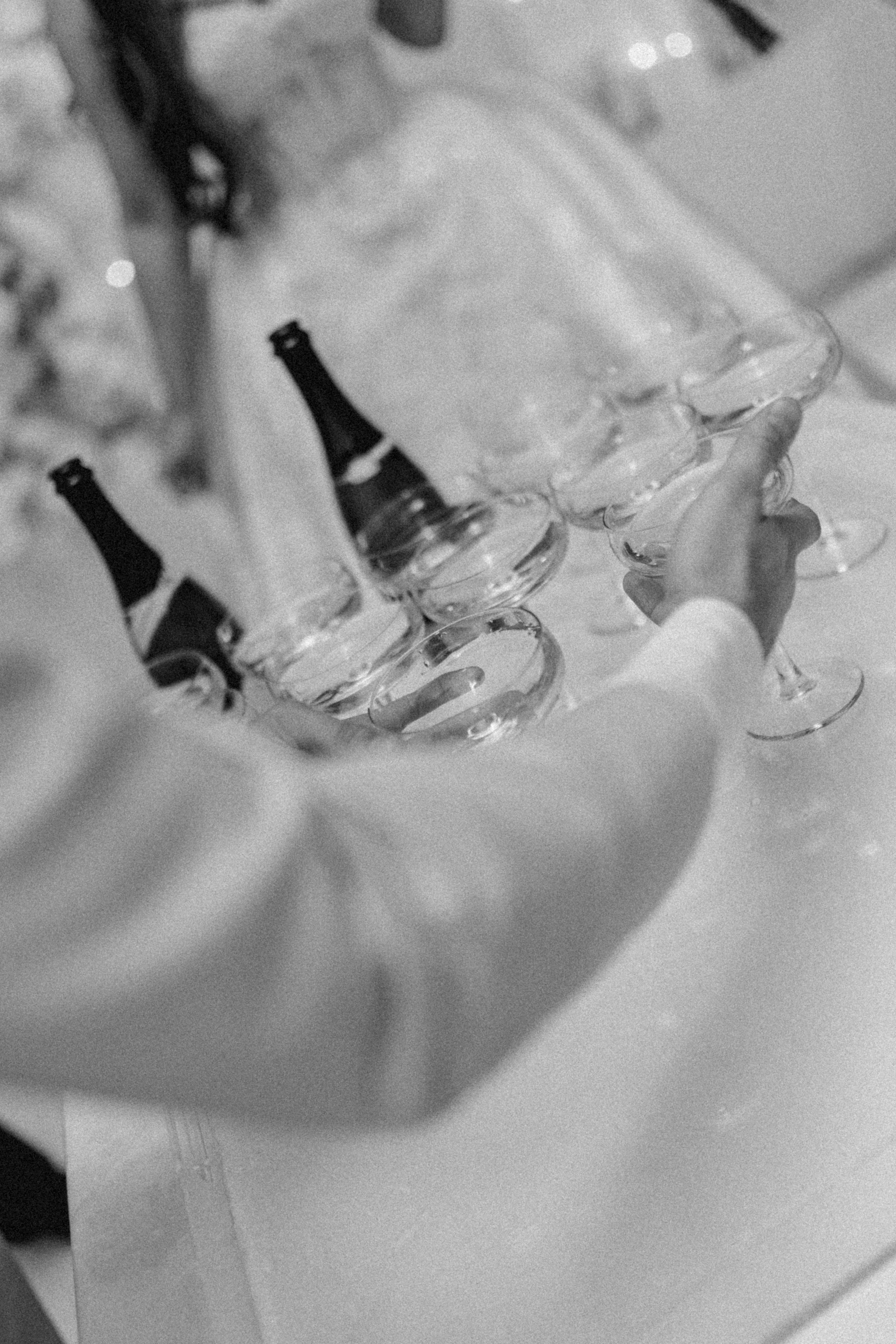 Black and white close-up of hands holding champagne glasses.