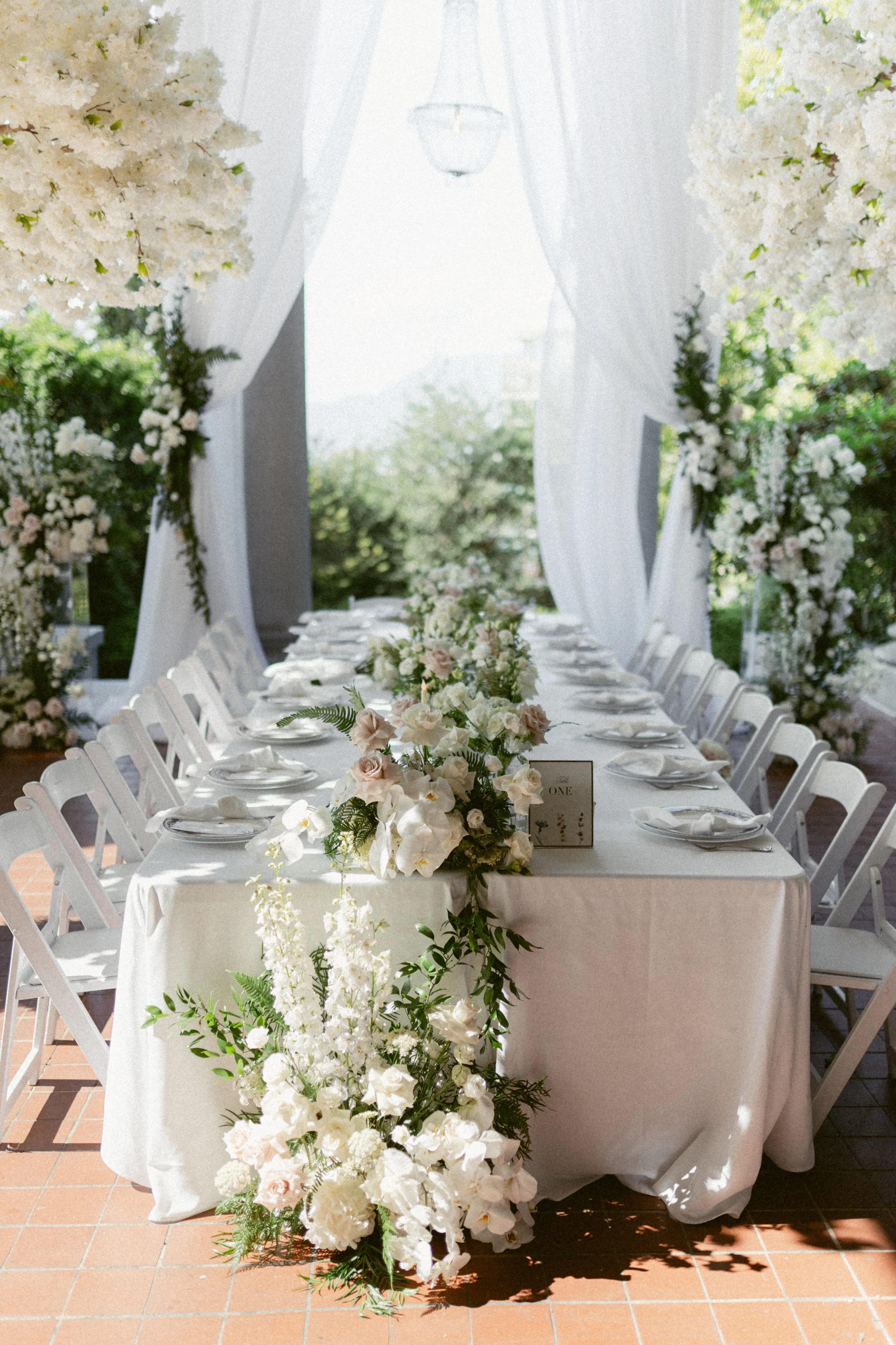 Outdoor wedding reception at Hycroft manor, with white floral cascading off the side of the table.
