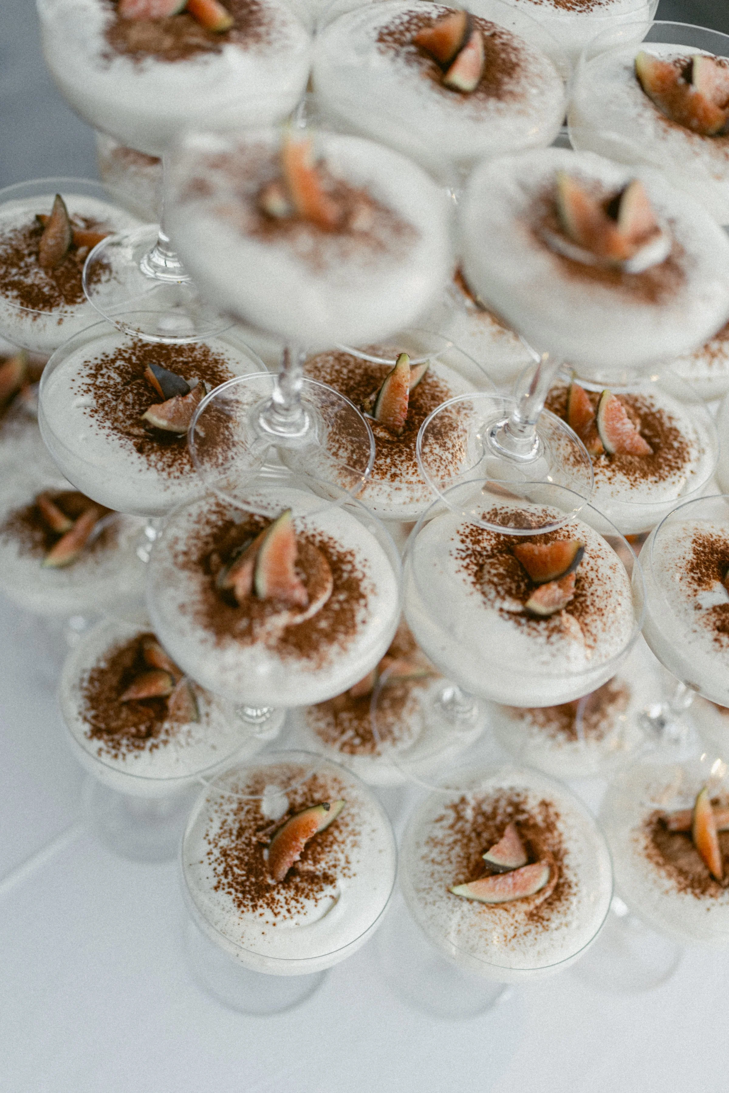 Dessert in a champagne coupe tower topped with fig garnish and cocoa dusting.
