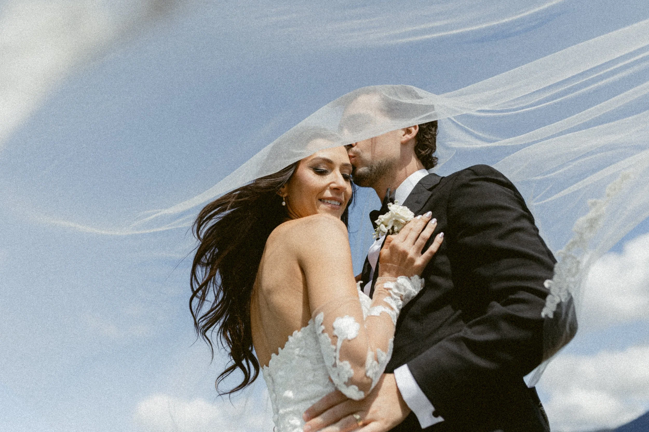 Romantic portrait of the couple beneath a flowing wedding veil in Pitt Lake.