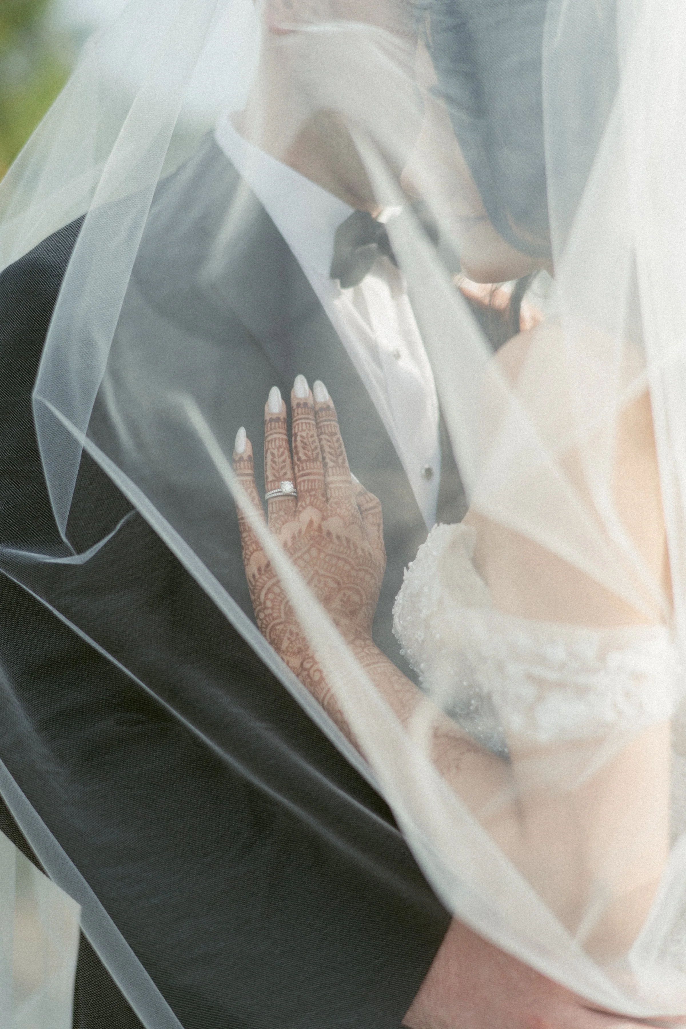Close-up of intricate henna and wedding rings beneath a sheer veil at Swaneset Bay Resort.