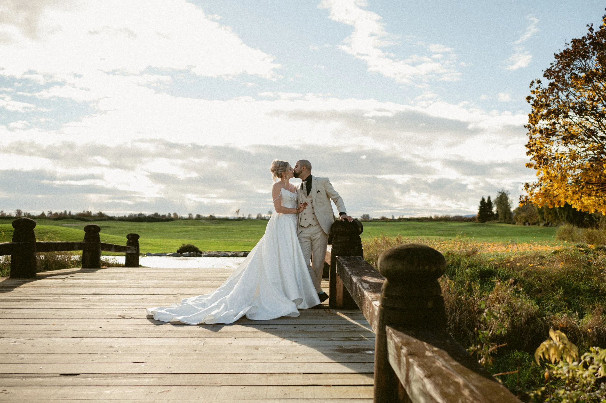 Bride and groom kissing on a wooden bridge at Swaneset Bay Resort.