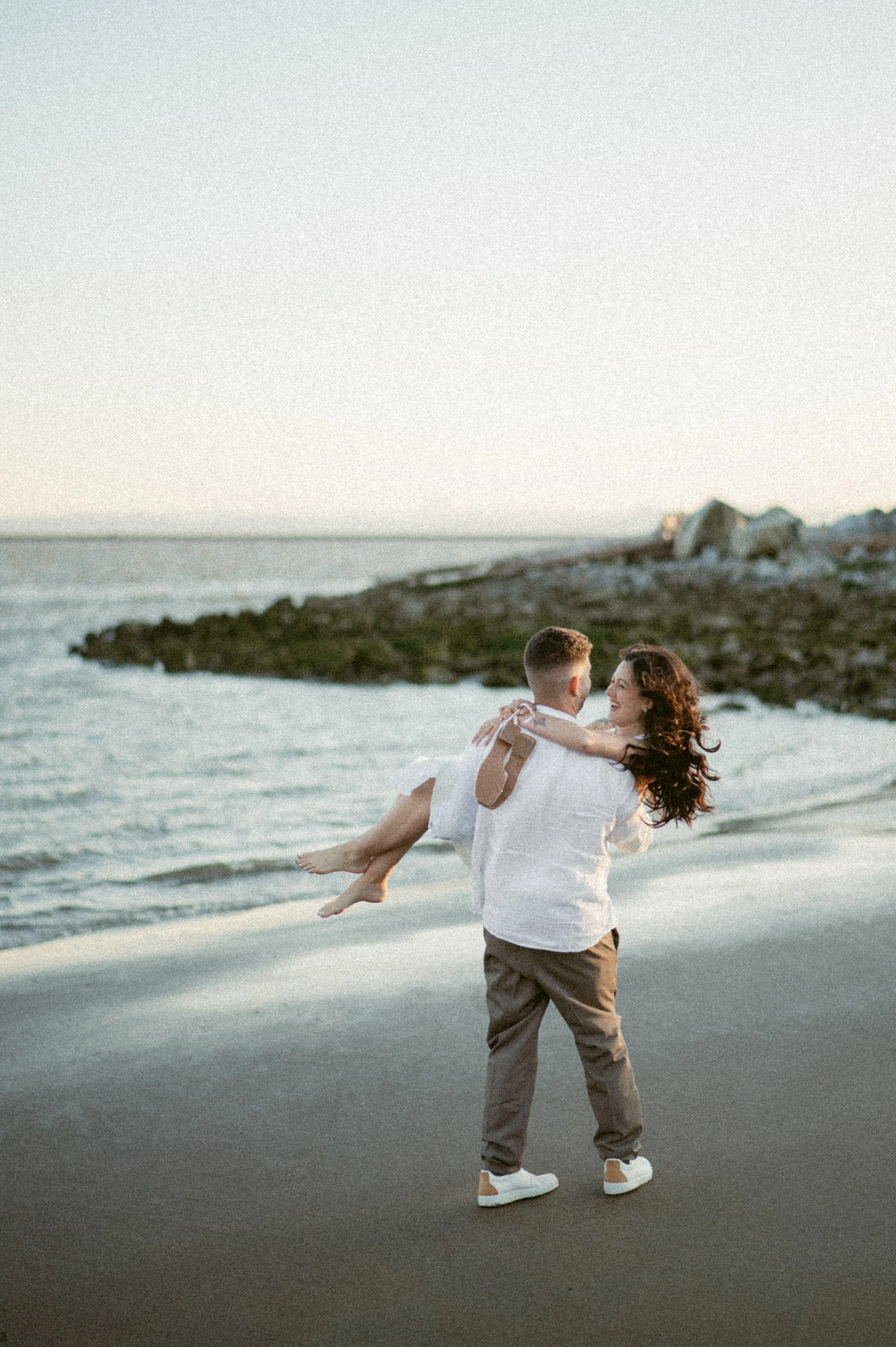 Playful engagement photo of couple by the ocean at Garry Point Park.