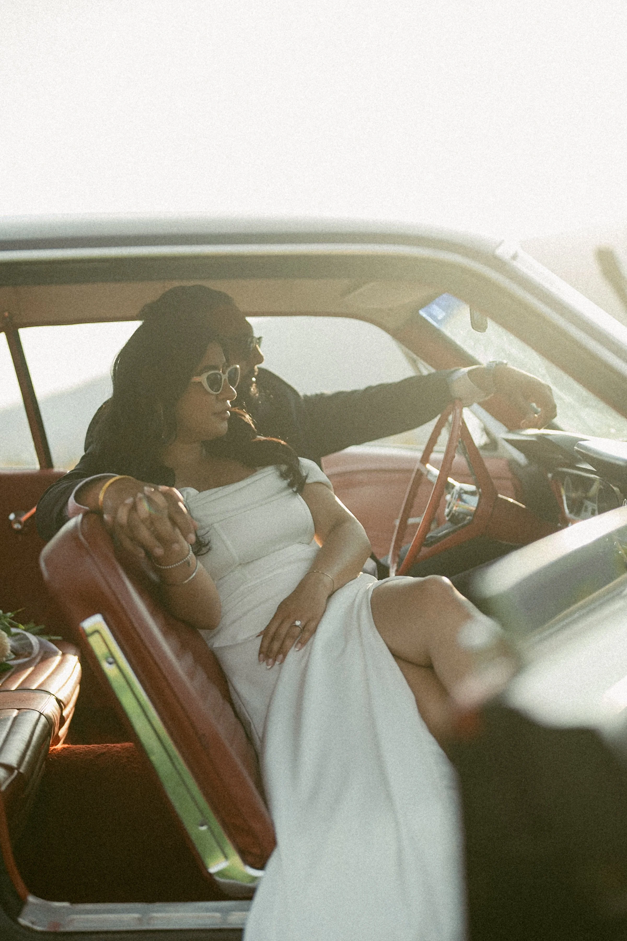 Couple relaxing together inside a vintage car at golden hour.