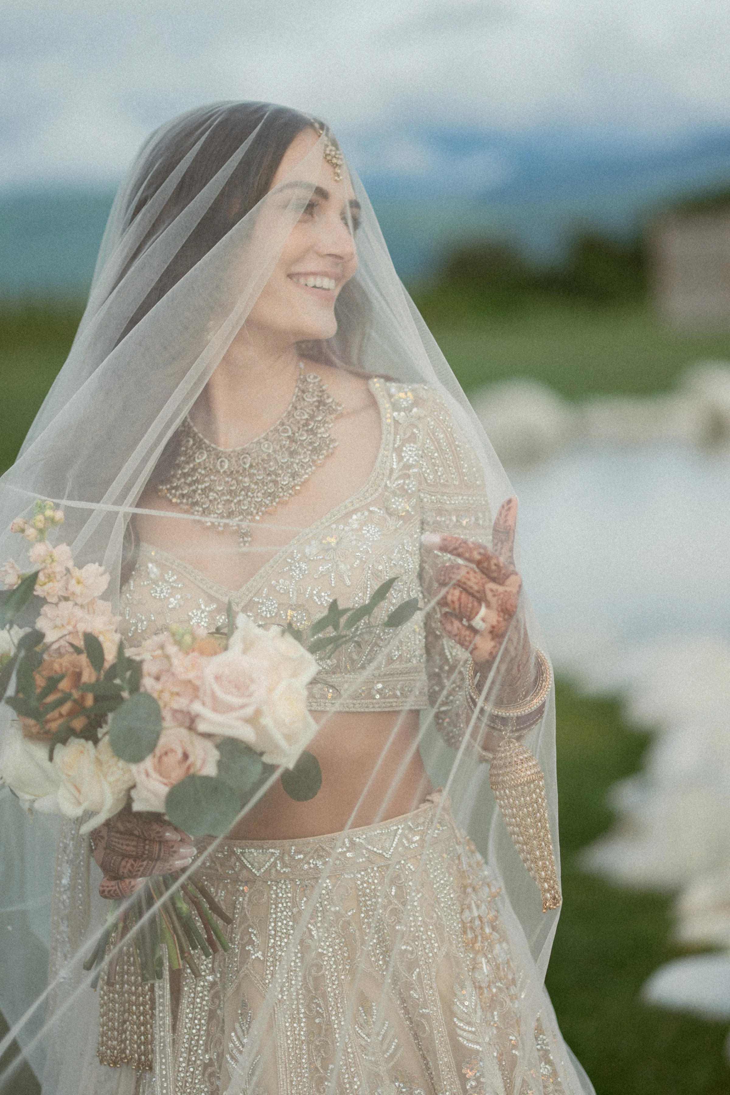 Bride smiles softly beneath a sheer veil at Mann Farms.