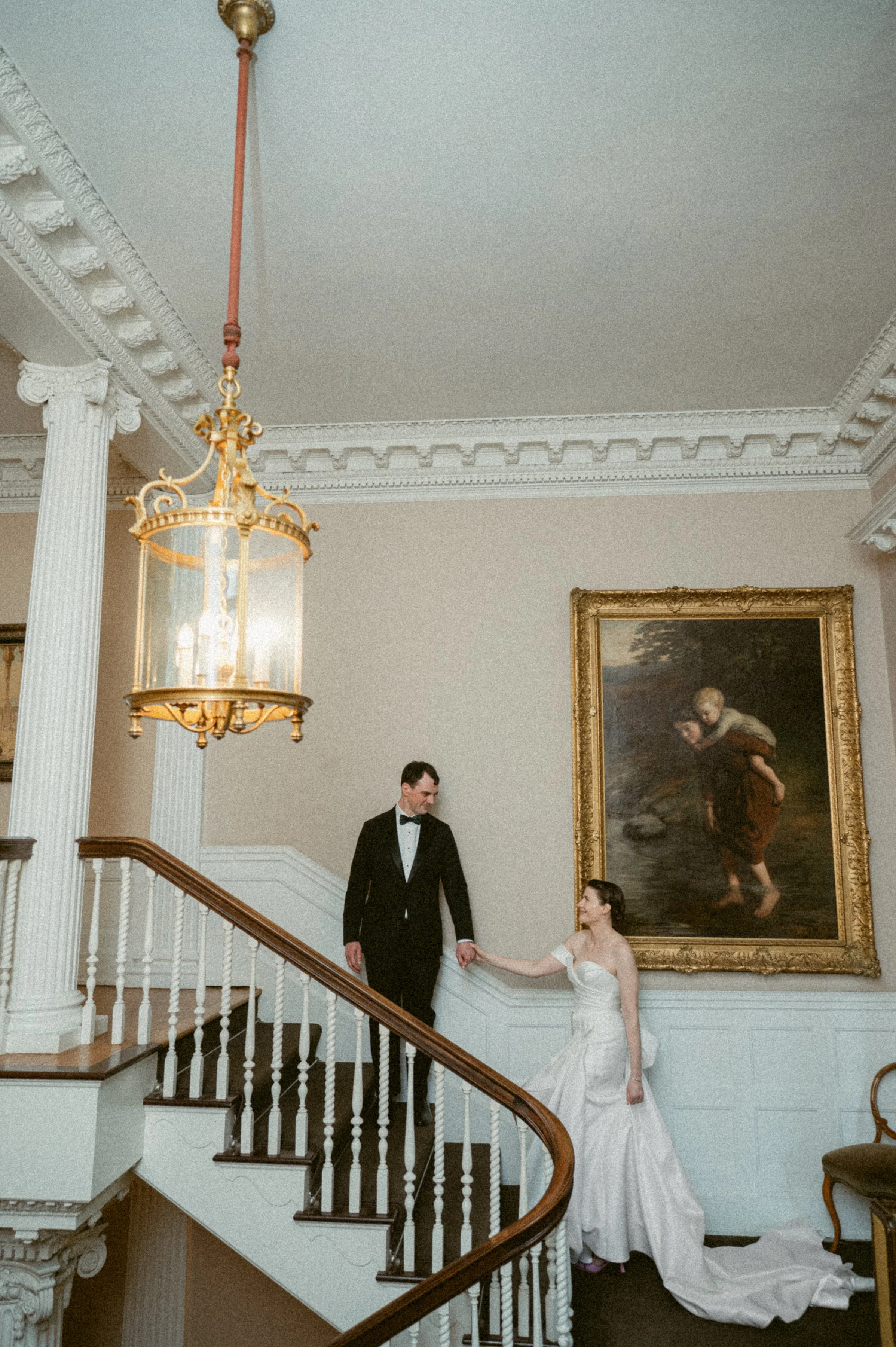 Wedding couple holding hands on the grand staircase at Hycroft Manor.