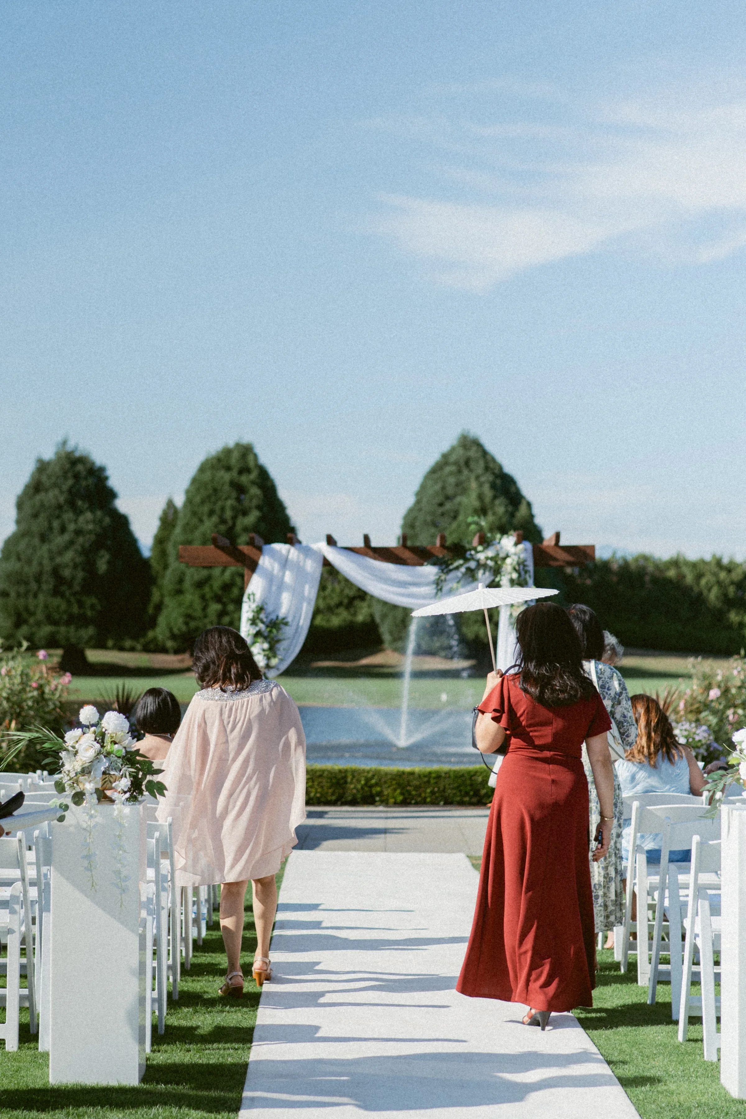 Wedding guests walking down the aisle toward an outdoor ceremony at Mayfair Lakes Country Club.