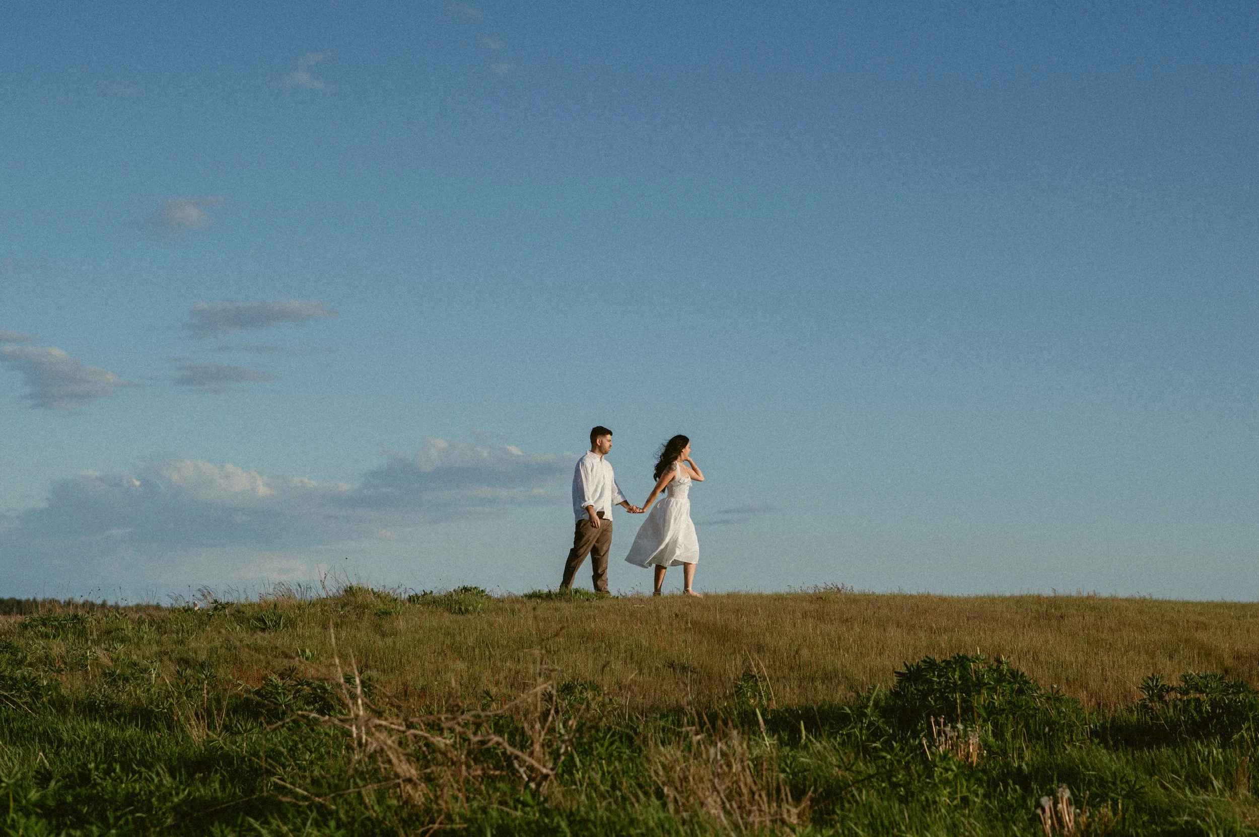 Couple walking hand in hand at golden hour at Garry Point Park.