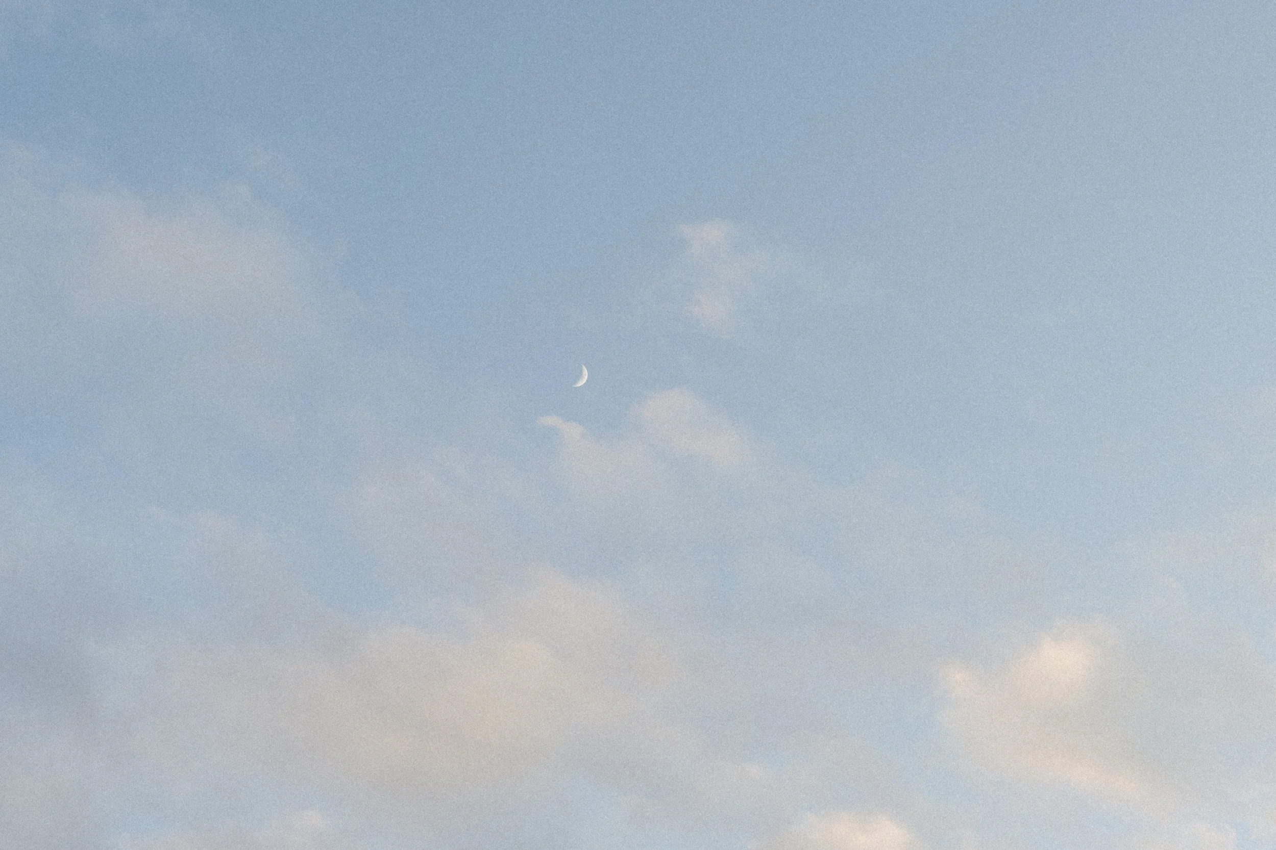 Soft blue sky with a visible crescent moon above the venue.