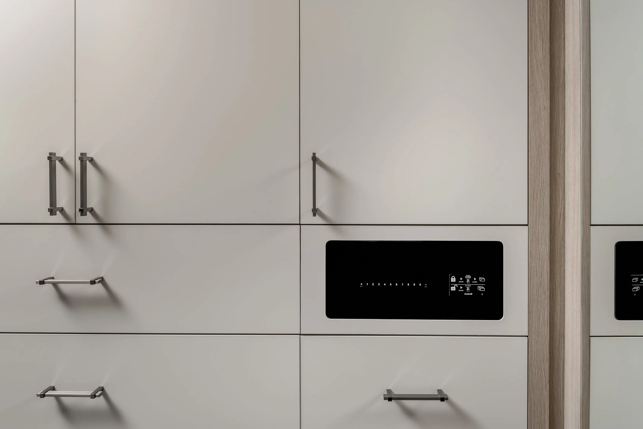 Modern kitchen with white cabinetry, black control panel, and wooden trim.
