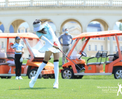 Portrait of a person with short black hair wearing a black T-shirt against a blue background.