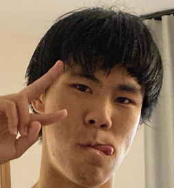 Young man making a peace sign with his fingers and sticking out his tongue, indoors.
