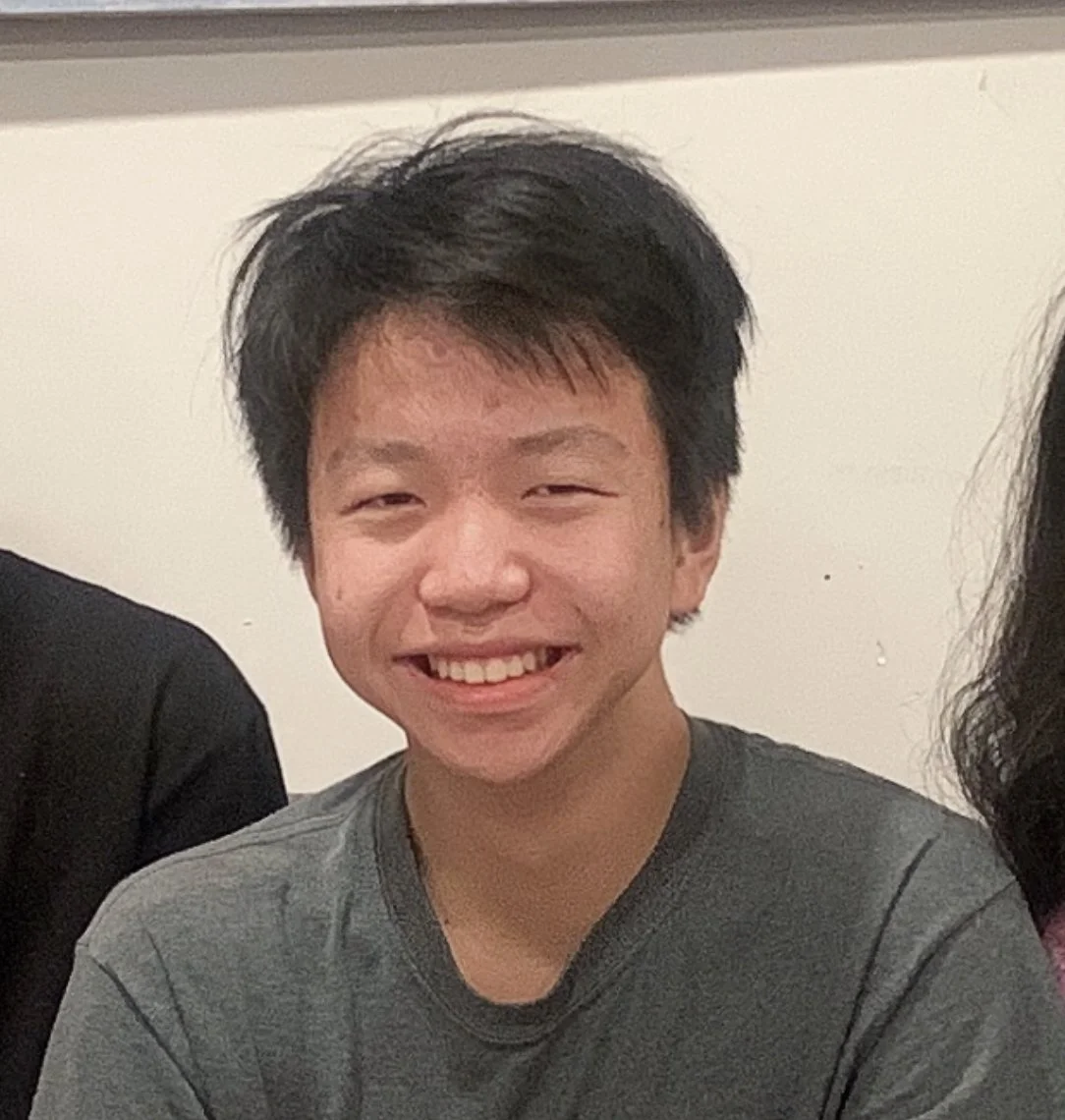 Smiling person in a gray shirt against a light background.