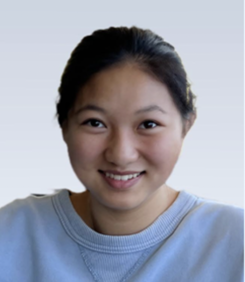 Person smiling, wearing a light blue sweater, with a neutral background.