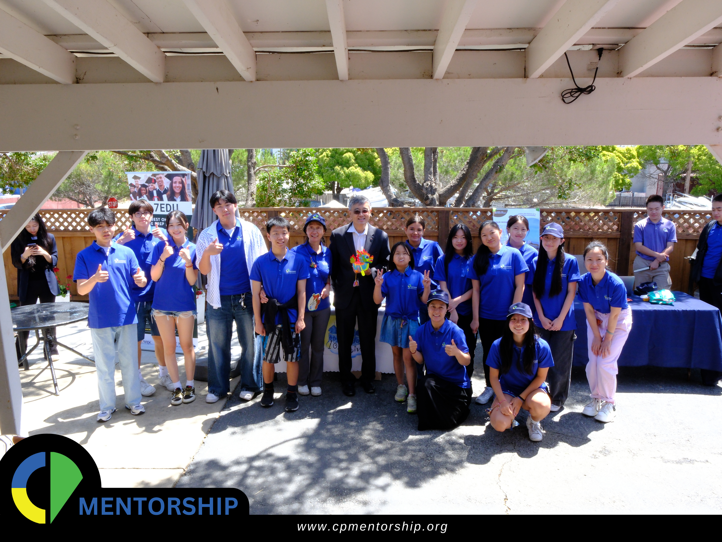 Group of people wearing blue shirts posing outdoors for a mentorship event.