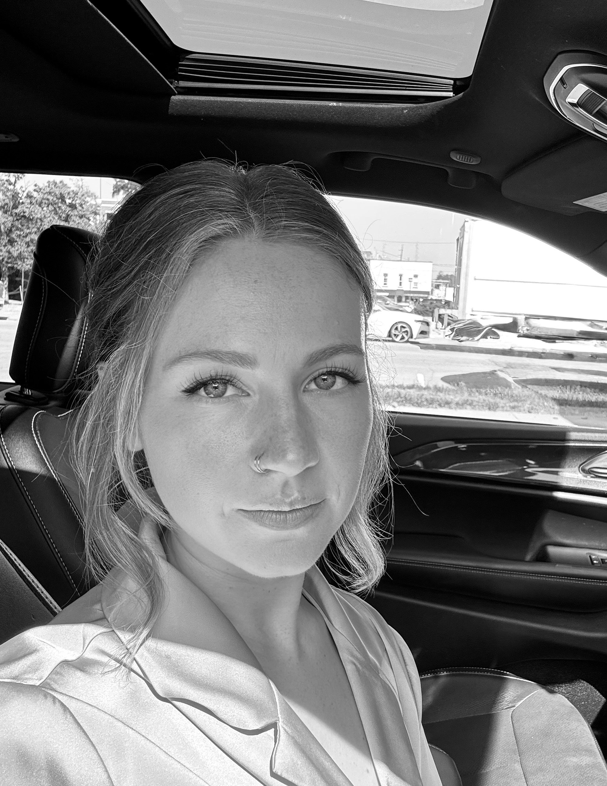 Julie Anne Hoeflinger is a 26-year-old nonfiction writer based in Toledo, Ohio. Black and white image of Julie in a car.