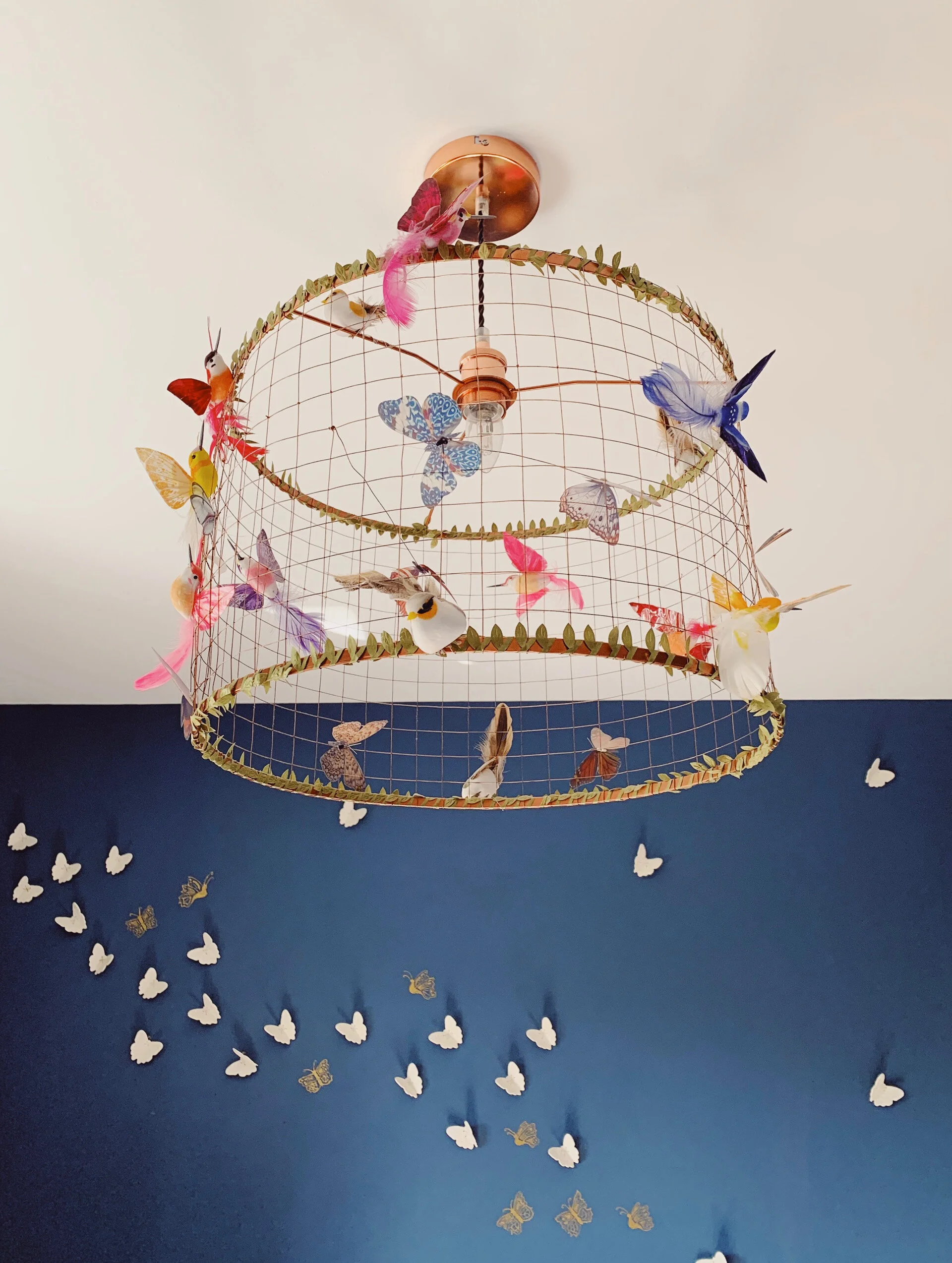 A light fixture surrounded by a wireframe of various birds that mimics a birdcage