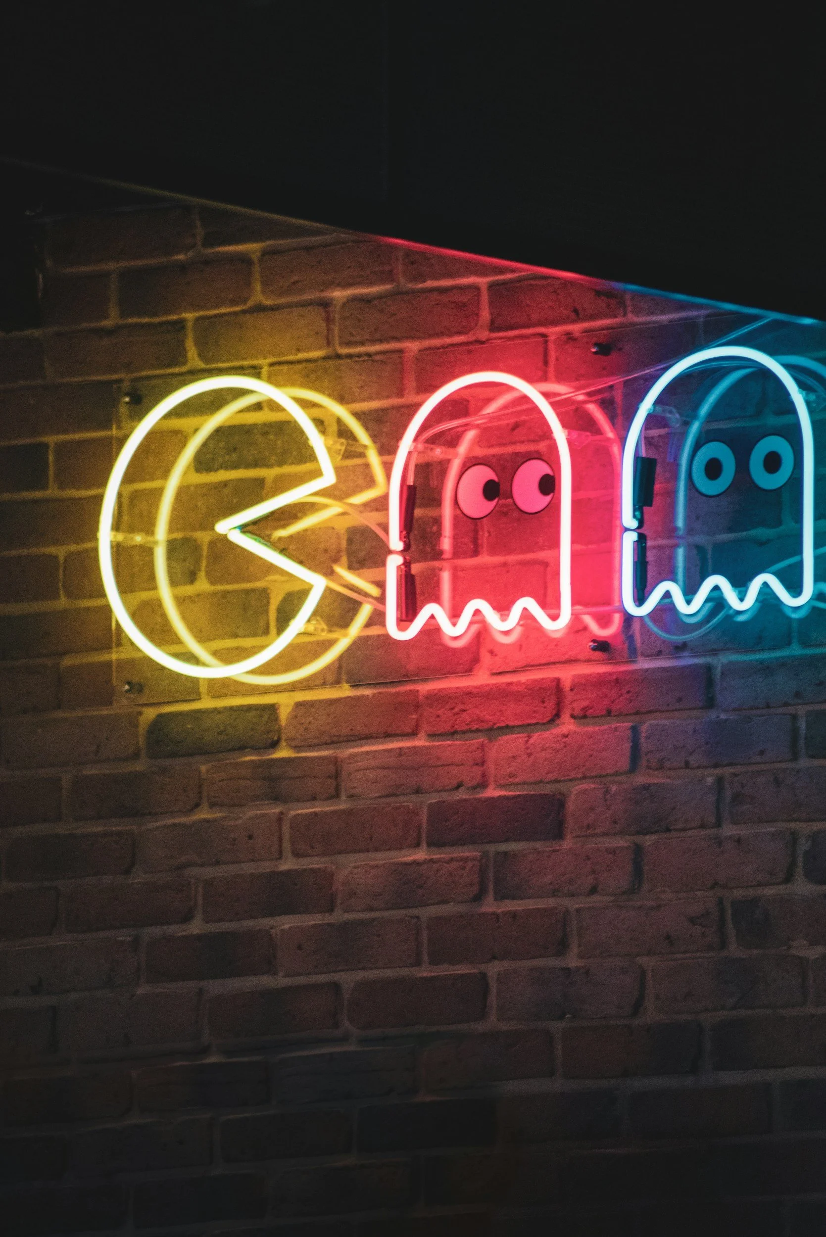 Neon sign of Pac-Man and ghosts on brick wall