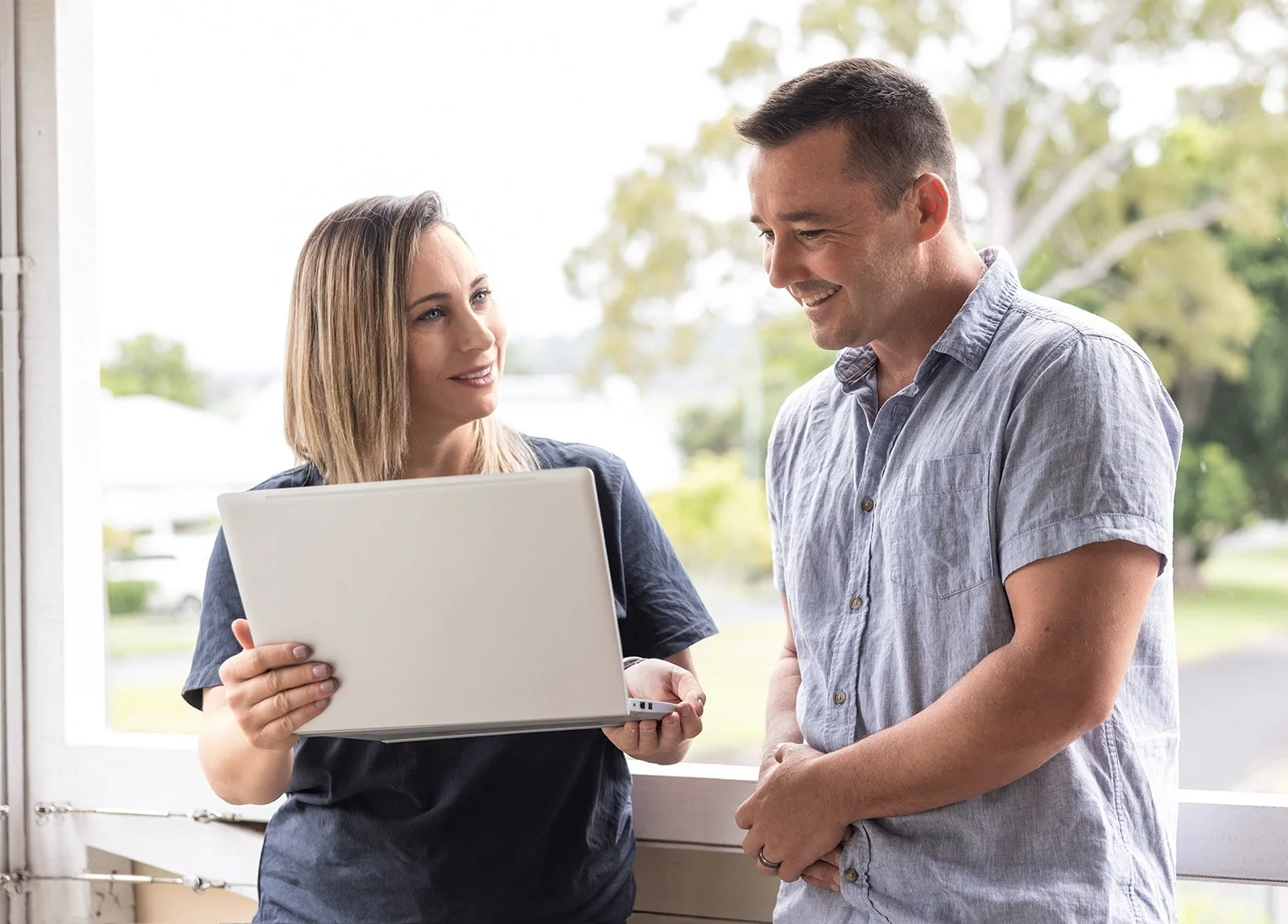 Scenic view of a lake surrounded by rolling hills and mountains under an overcast sky.