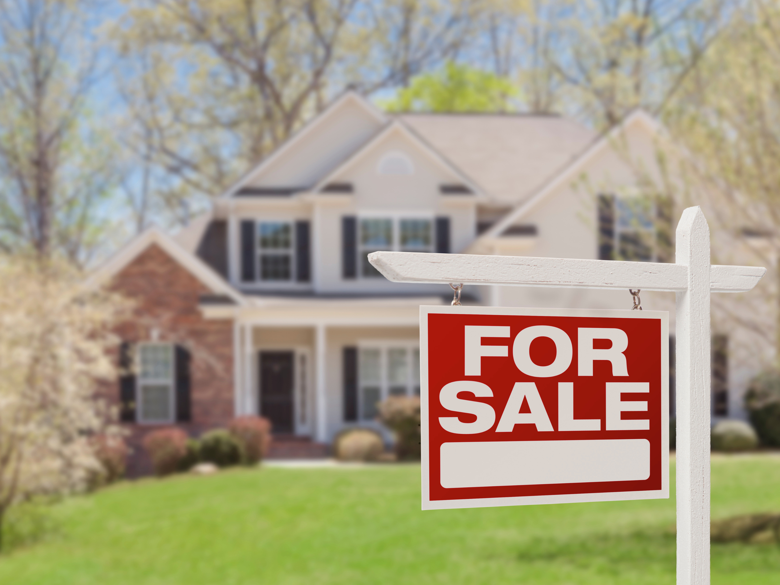 Beautiful house with red for sale sign in the front yard