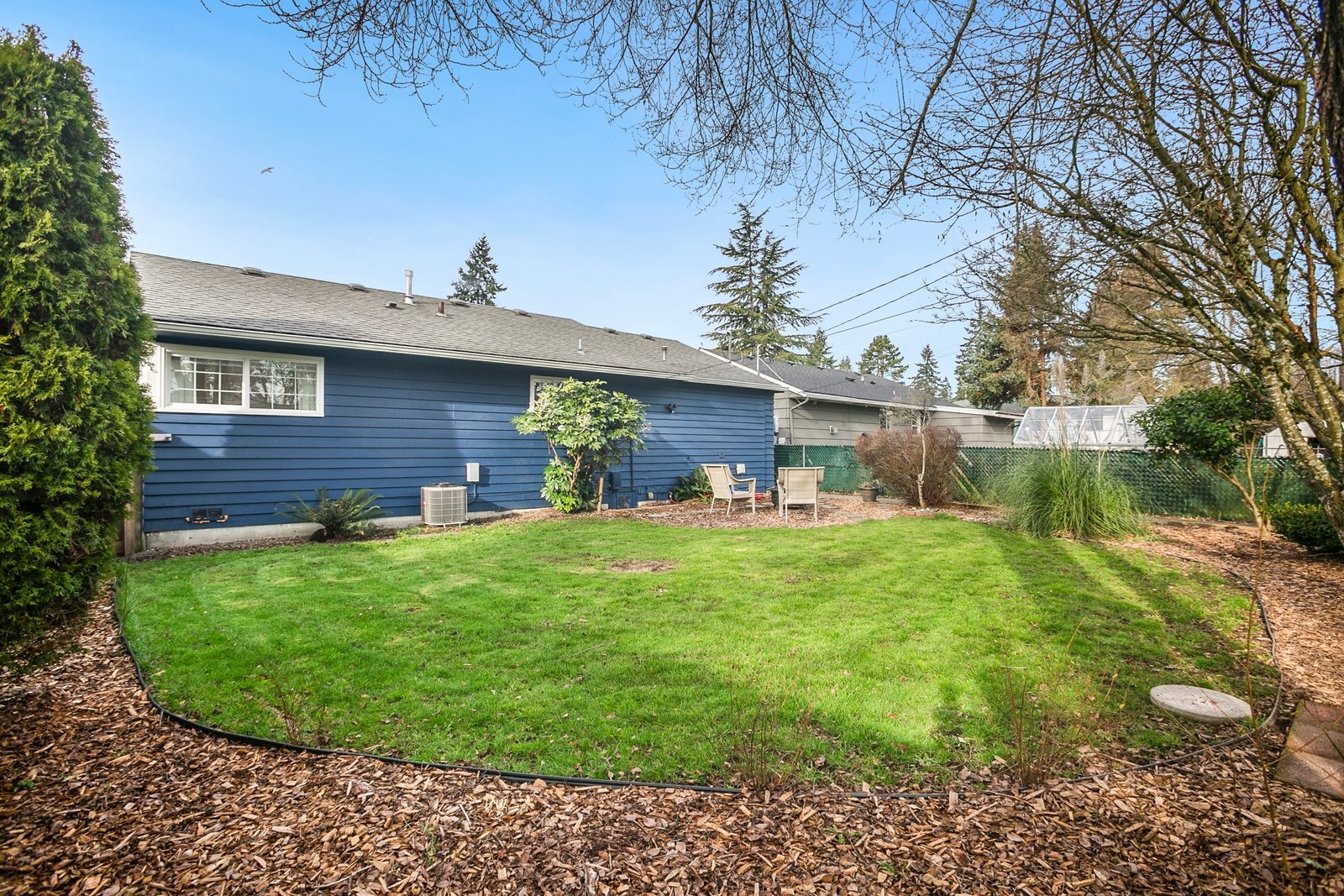 Modern dining room with wooden table, brown chairs, stone fireplace, and large windows.
