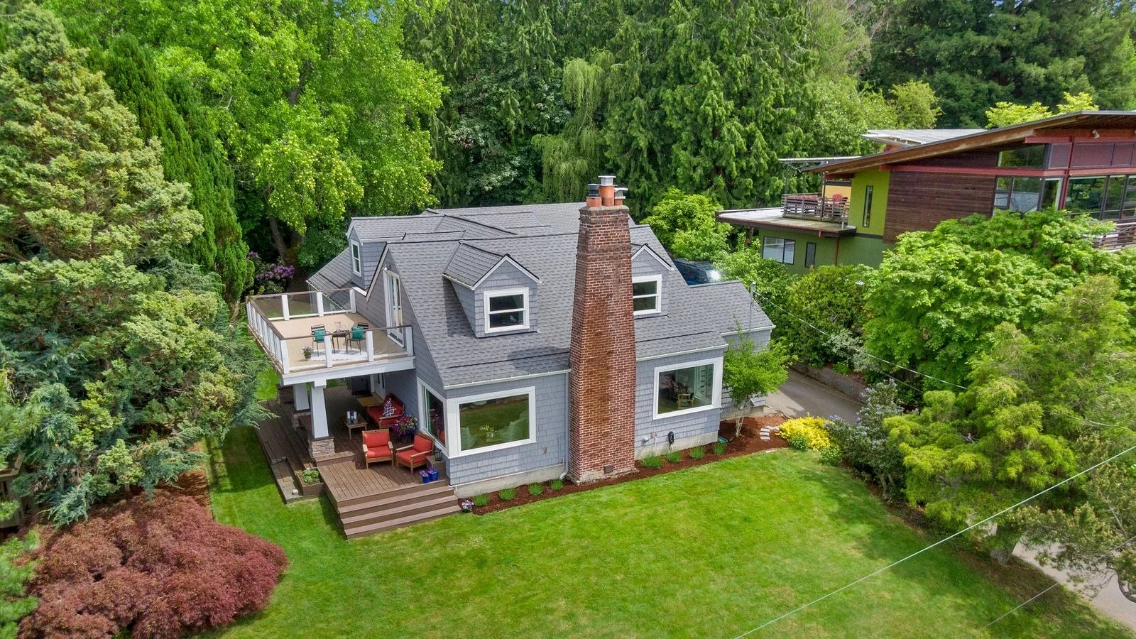 Gray house surrounded by trees with balcony.