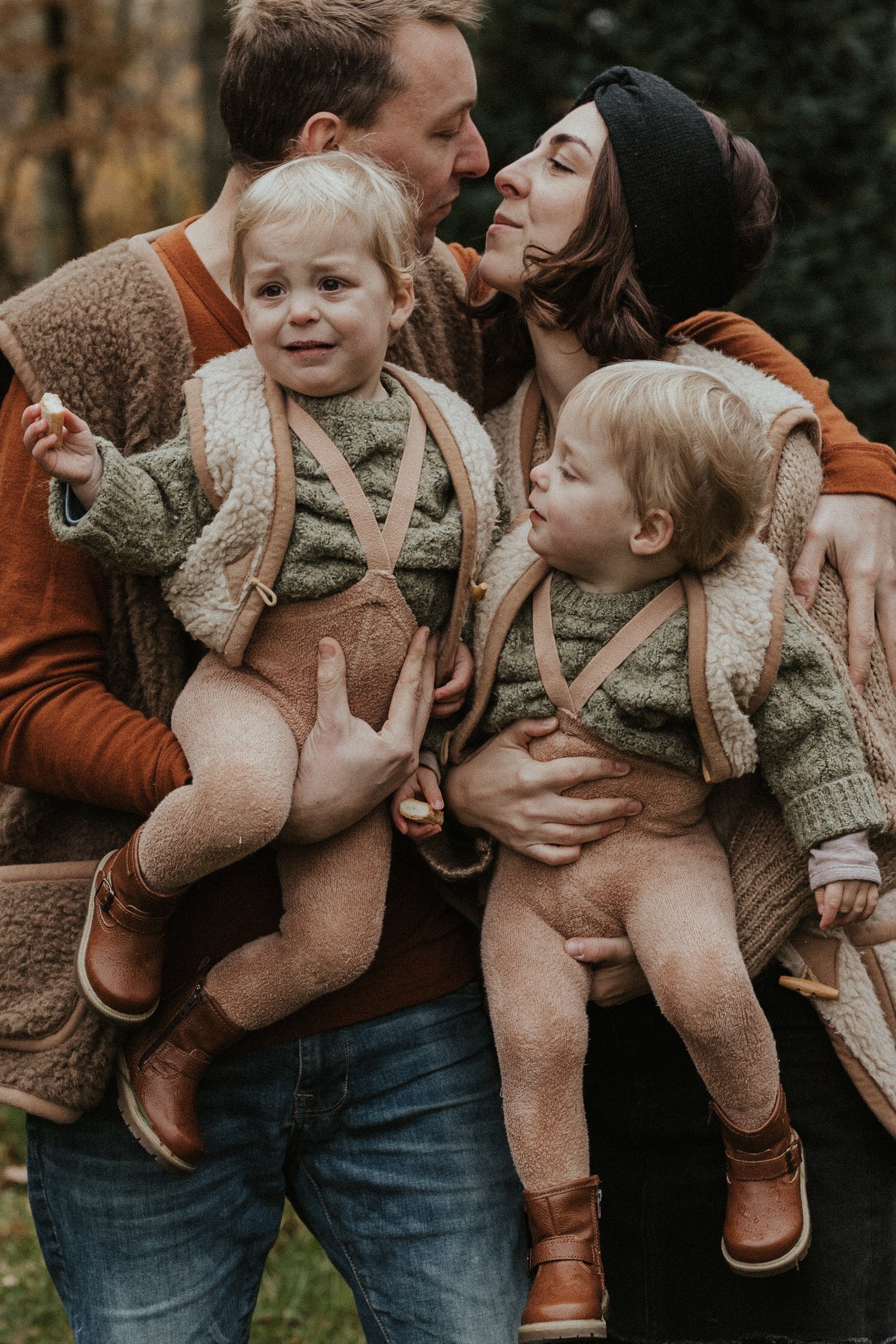Een foto van een mama en papa die hun tweeling vasthoudt in een bos in Mol