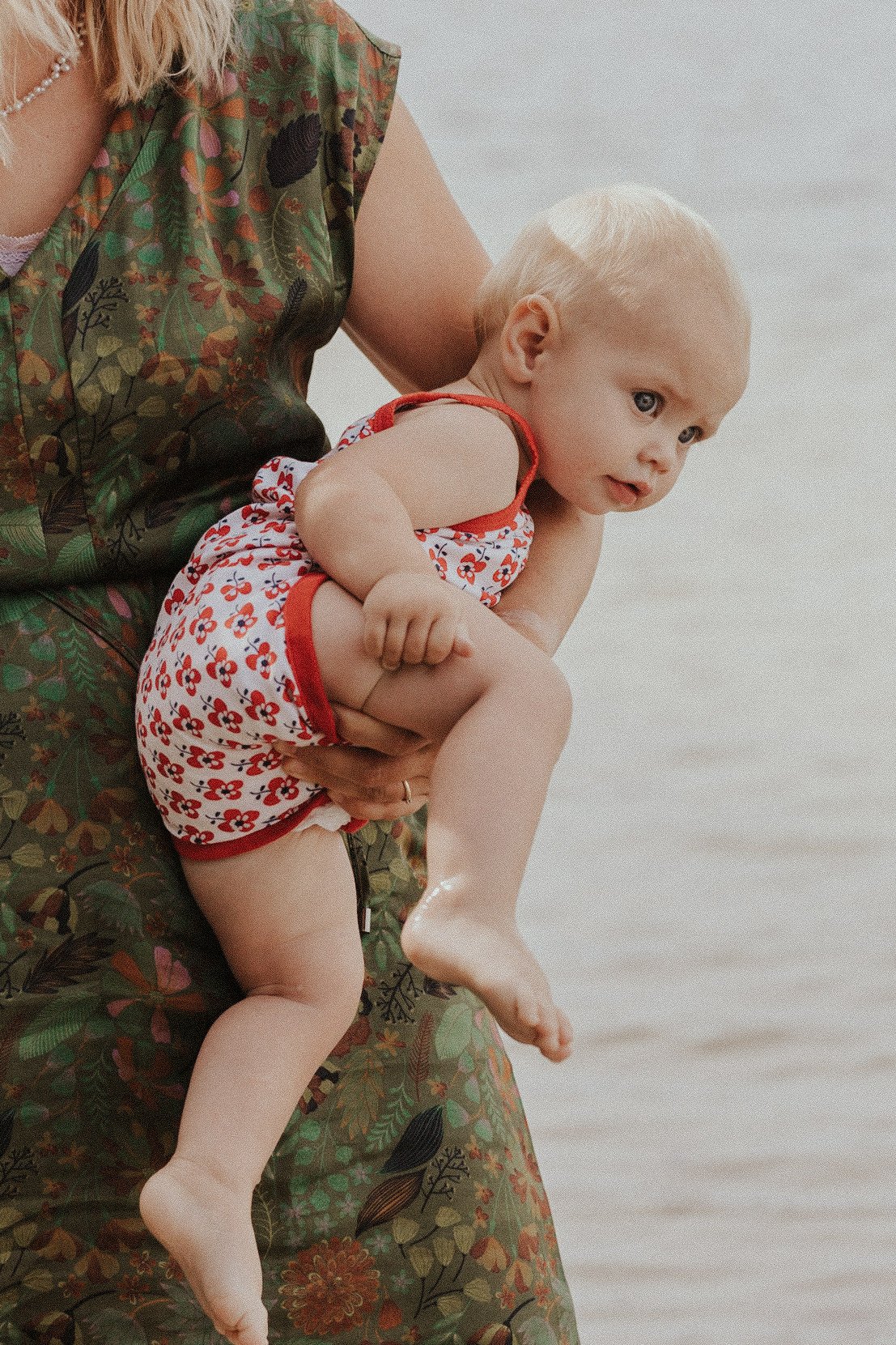 Foto van een baby meisje op de arm van haar mama aan het water in Mol