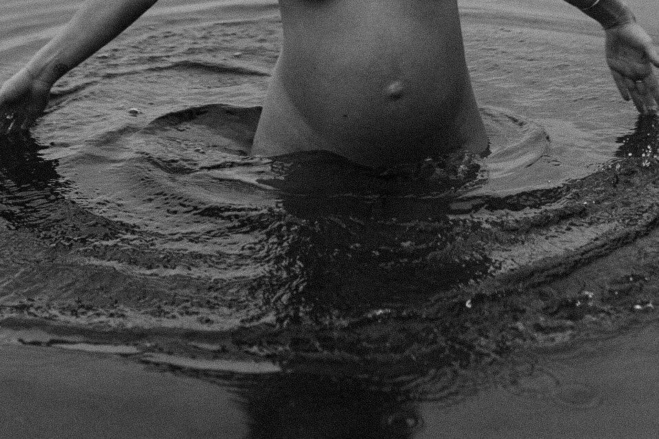 Een close-up van een zwangere vrouw die in het water staat in een meer in Mol