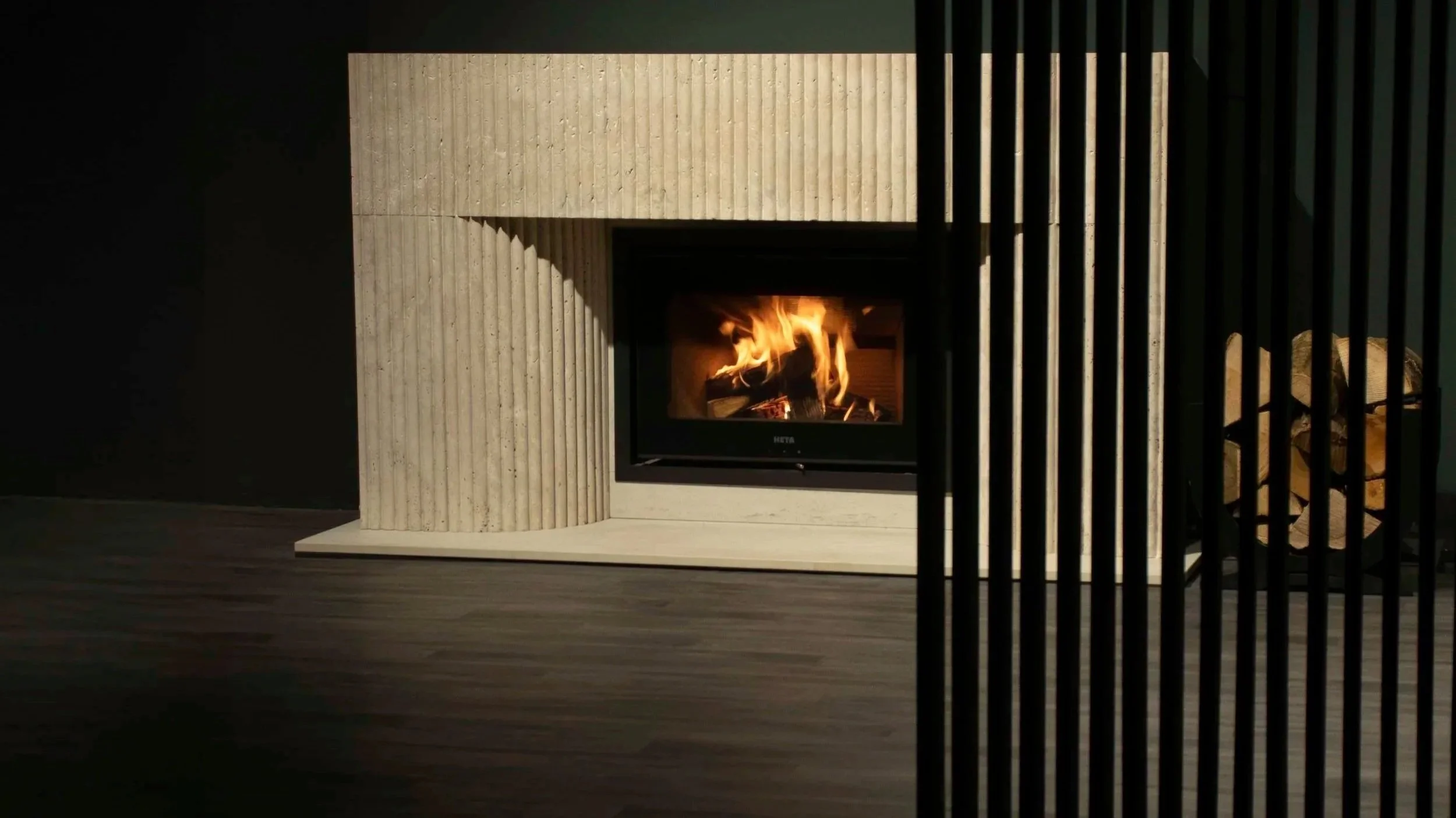 fluted limestone fireplace with a lit wood burning heta stove
