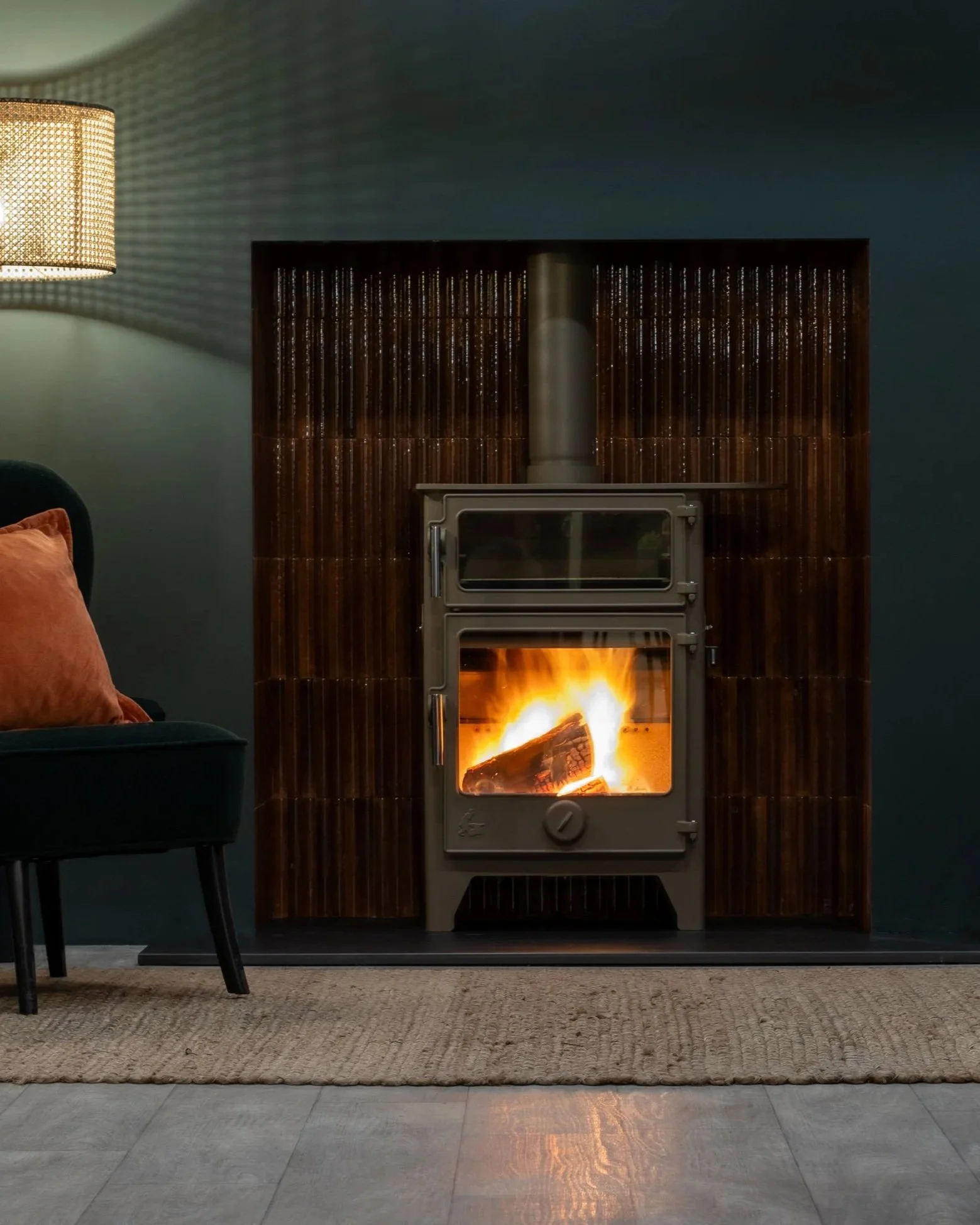 A photograph showing a lit Dean Forge wood burning stove with brown tiles in the chamber