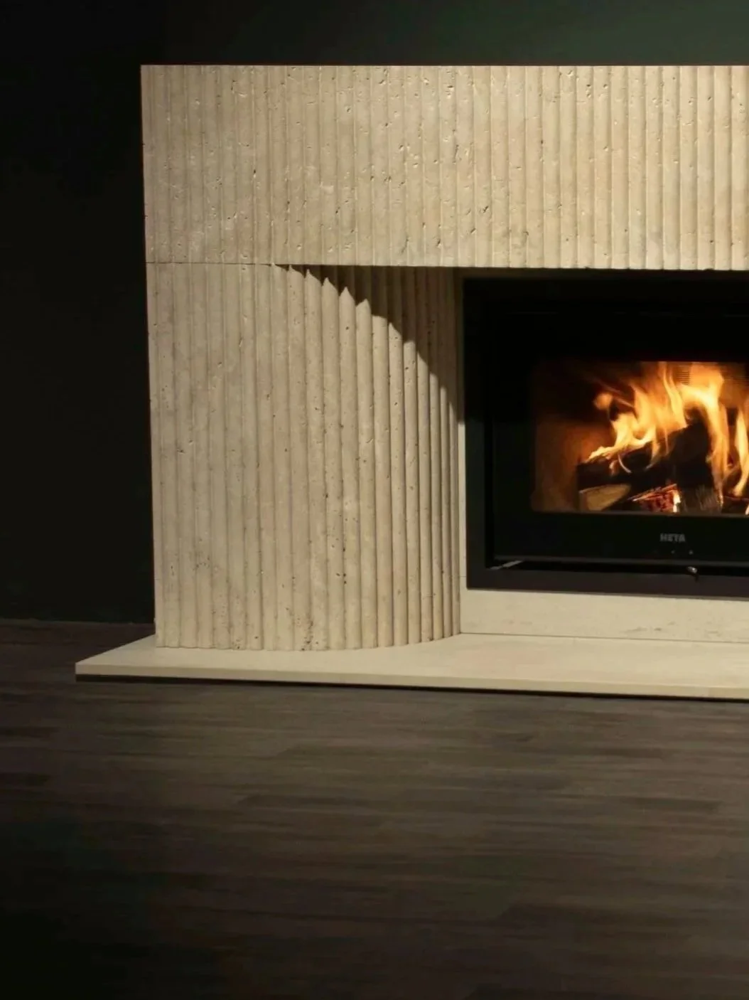 fluted limestone fireplace with a lit wood burning heta stove