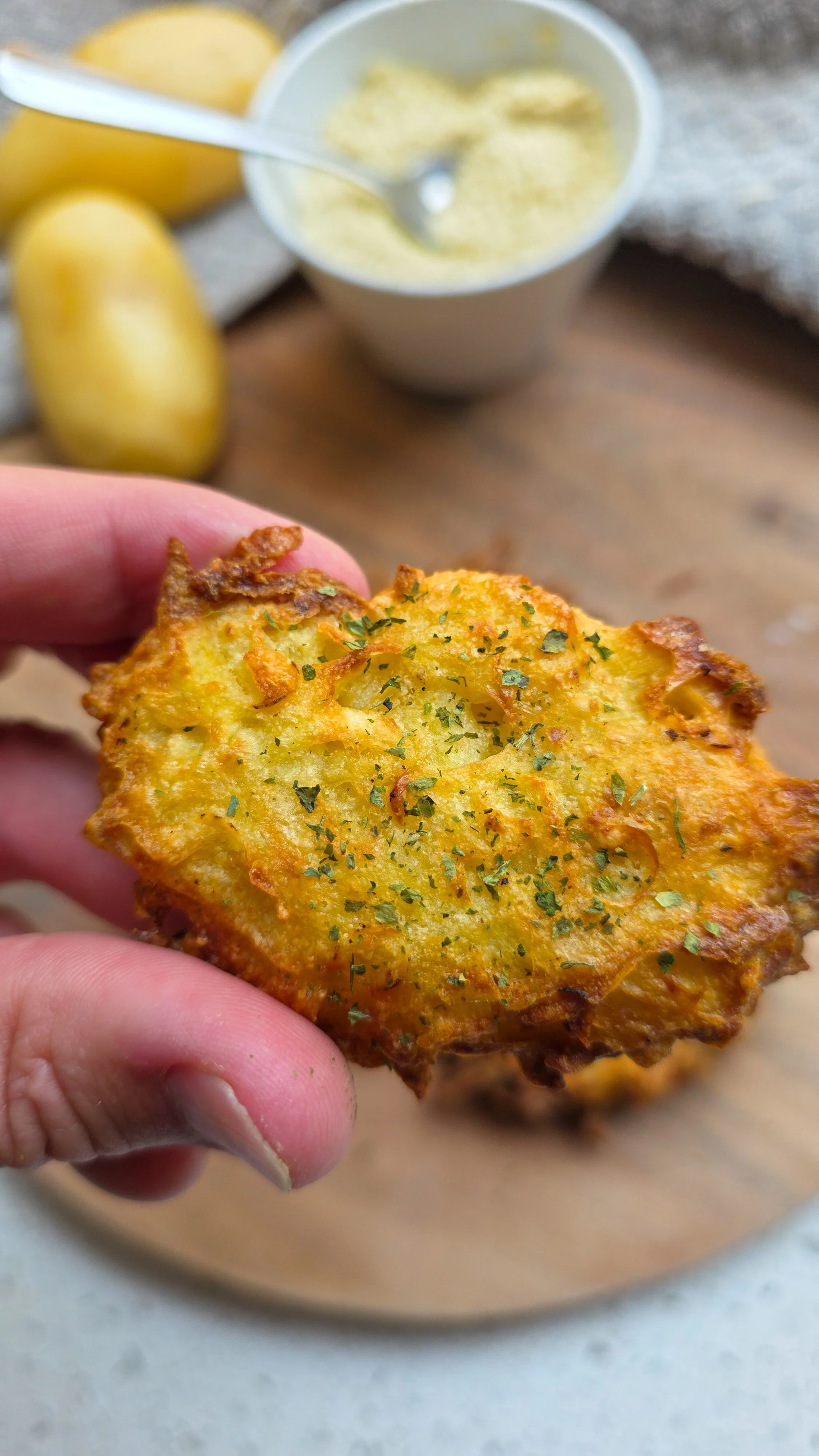 Close up of vegan hash browns with potatoes in background