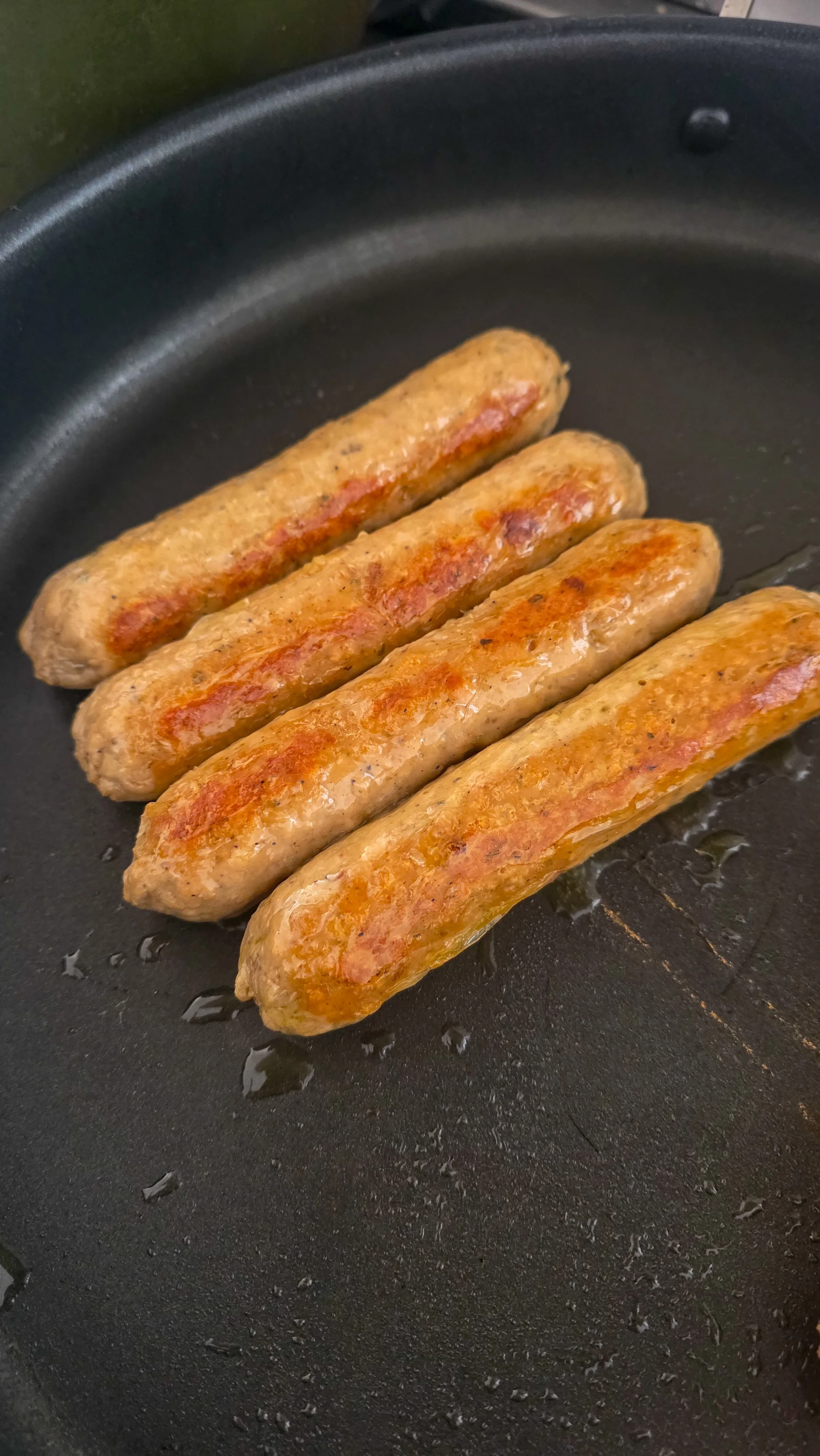 Impossible sausages cooking in a pan