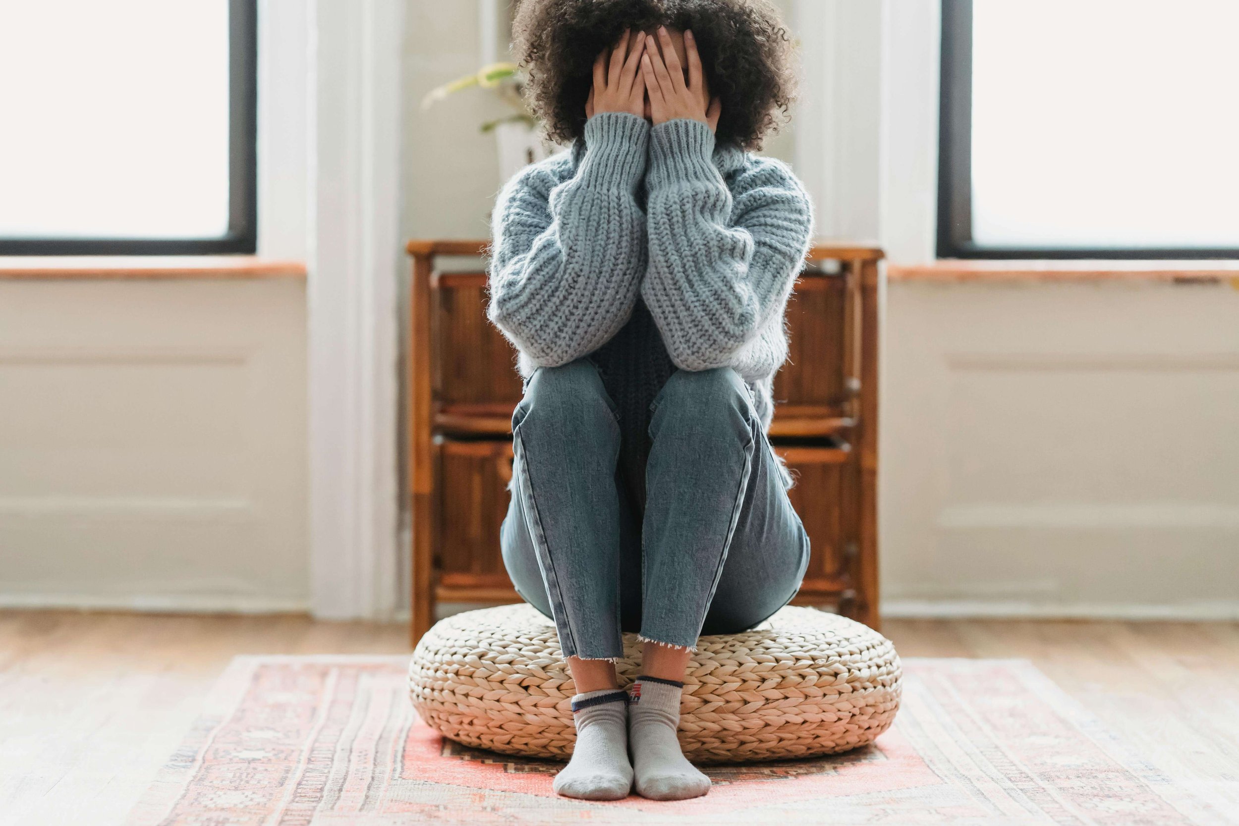 Person sitting curled up with hands covering their face, reflecting emotional distress, overwhelm, and the need for anxiety therapy for restrictive eating in Erie, PA.