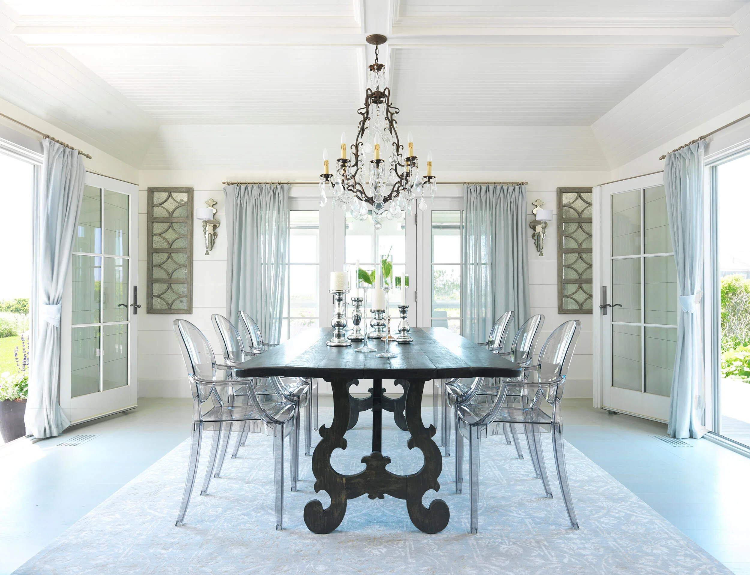 Dining Room with Chandelier, Large Black Table, and Clear Chairs in Nantucket Home