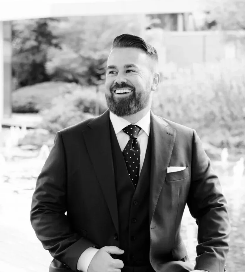 Man dressed in a suit and tie smiling off camera