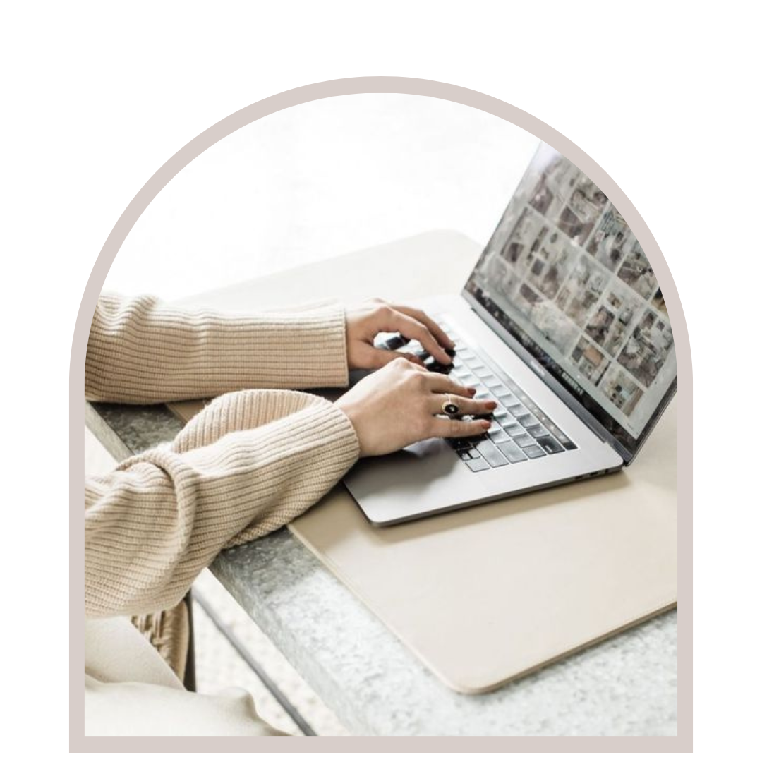 Person using a laptop to view a photo gallery, seated at a desk with a beige workspace mat.