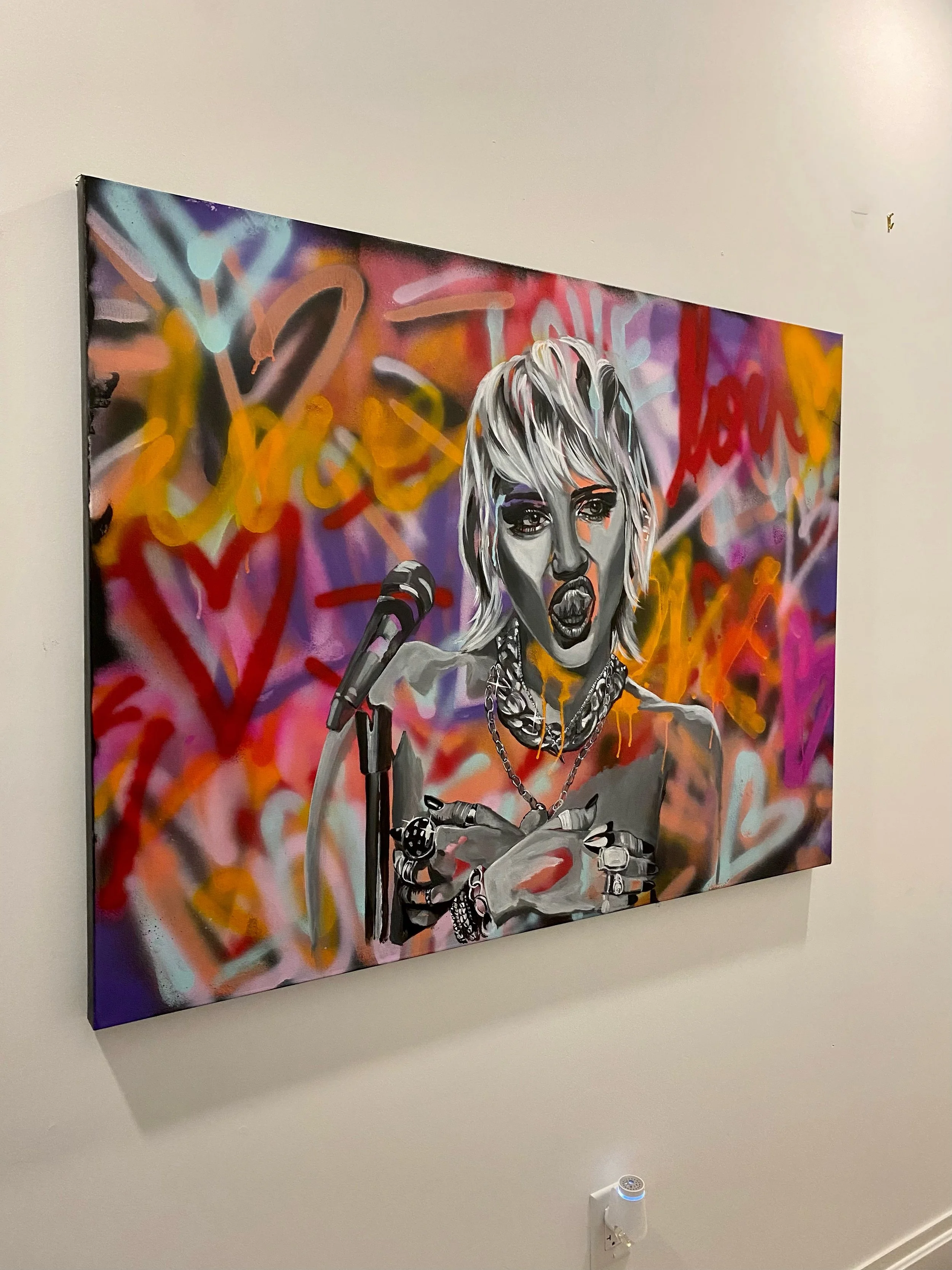 Street art portrait of a woman with short, blonde hair singing into a microphone, surrounded by colorful graffiti including hearts and words.