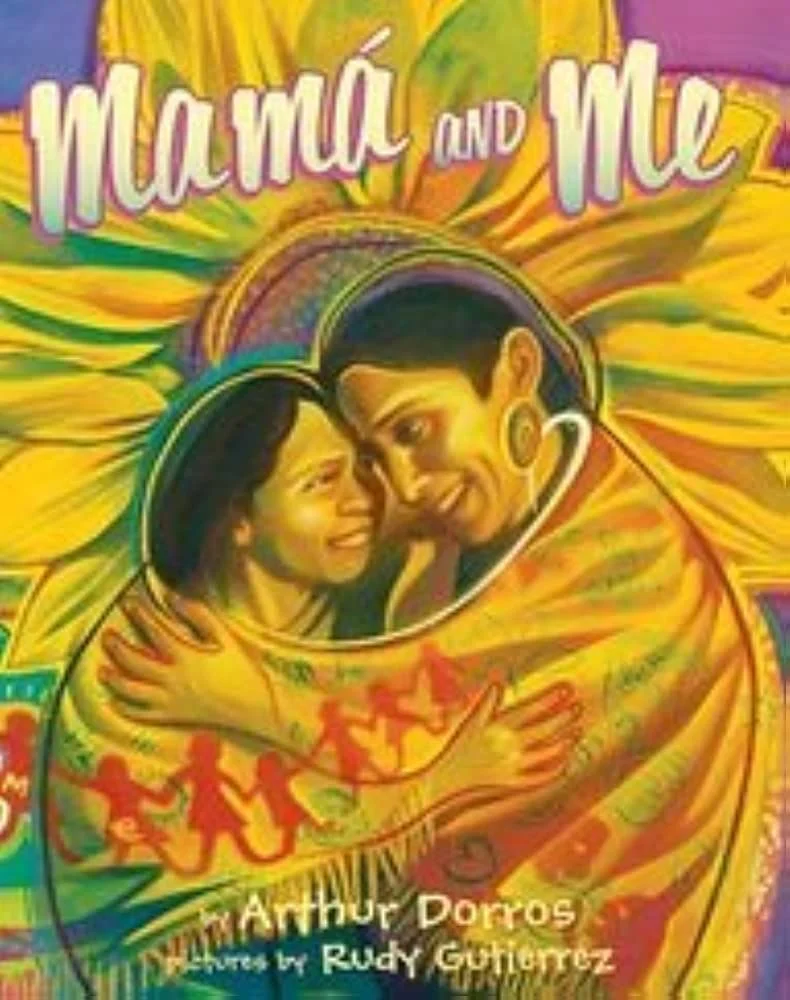 A mother and child wrapped in a colorful yellow blanket, holding each other and laughing with a large sunflower behind them.