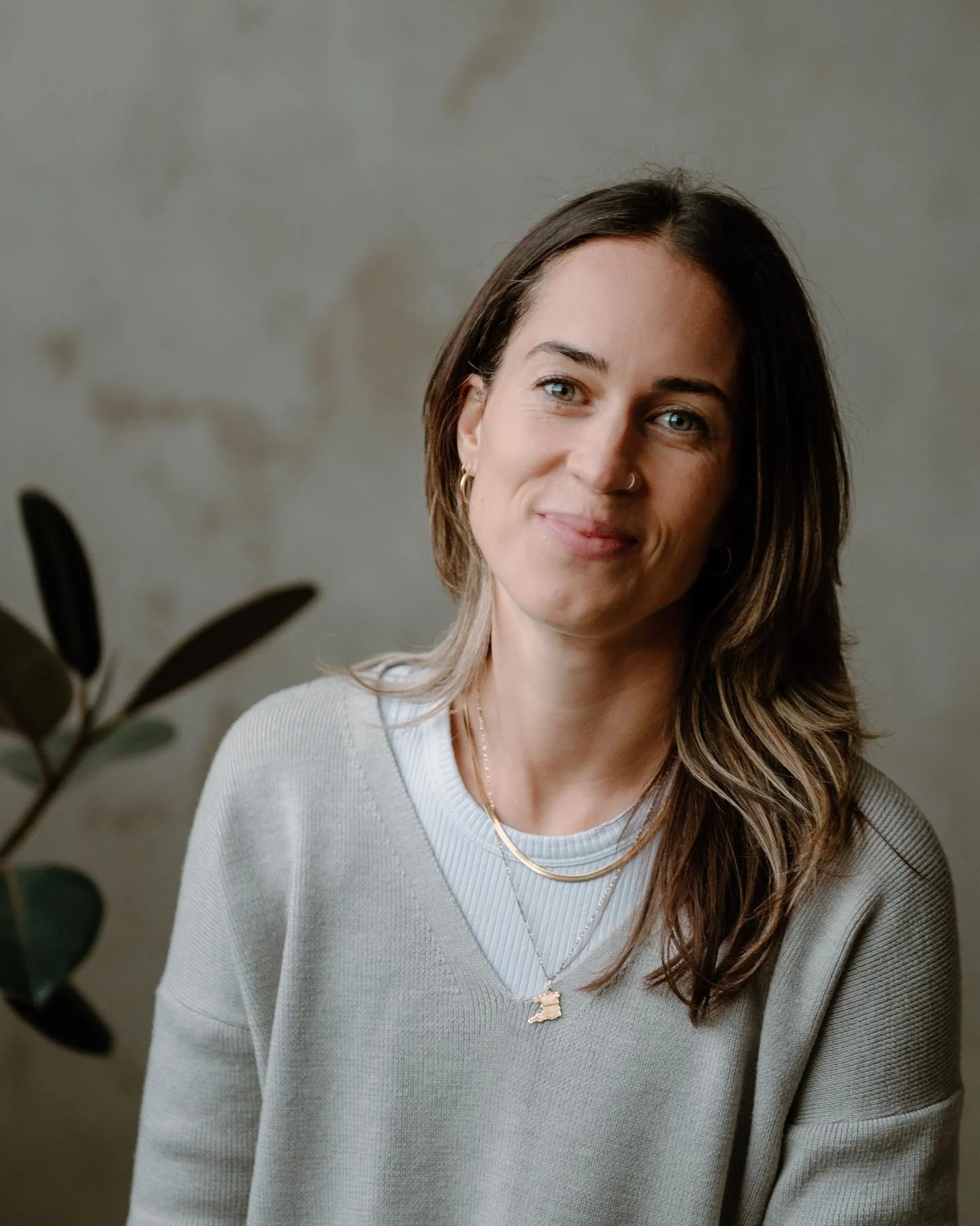 Image of Meaghan's face, looking towards camera with a smile and inviting eyes, on a warm grey background