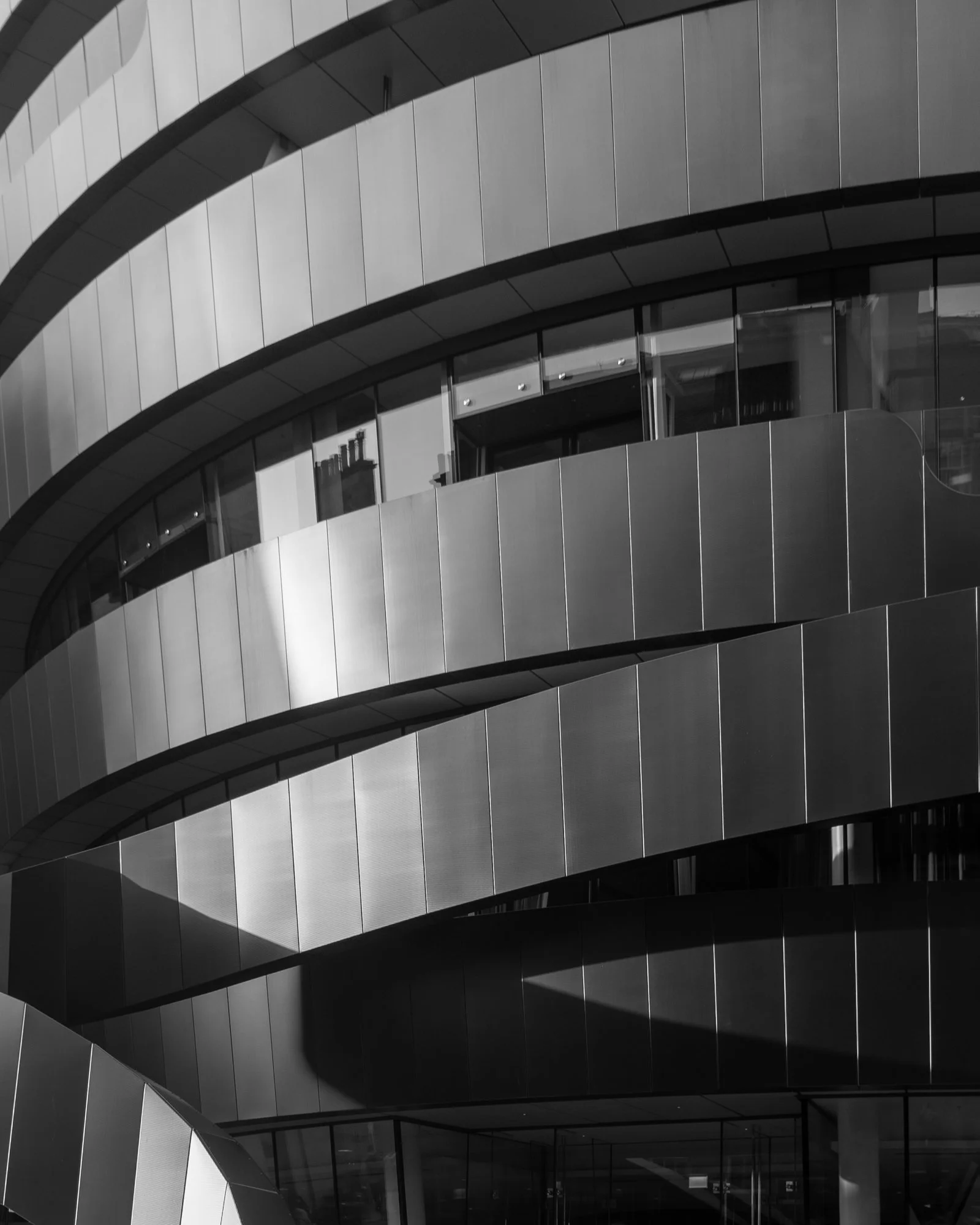 Modern building with curved, metallic panels and large glass windows.