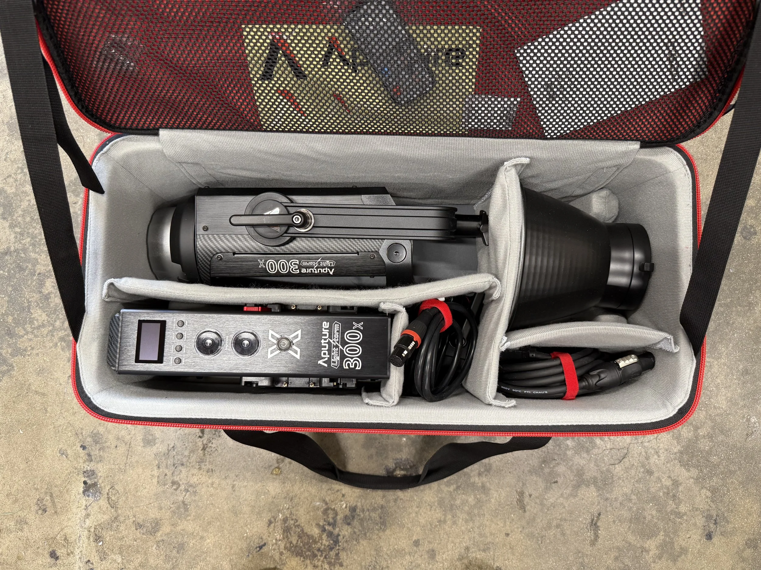 Open carrying case with a camera slider and remote control, some cables, and a flashlight inside.